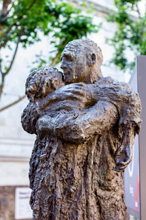 A bronze sculpture depicts a man hugging a child.