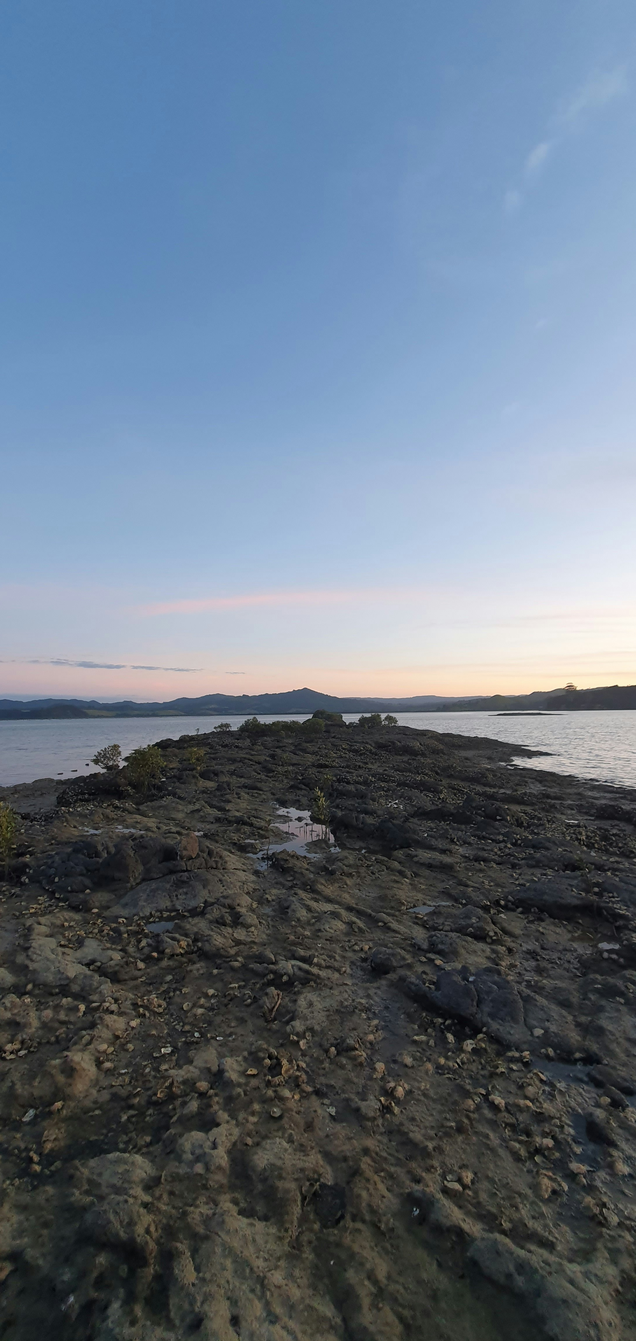 Rocky land extends into the serene water.