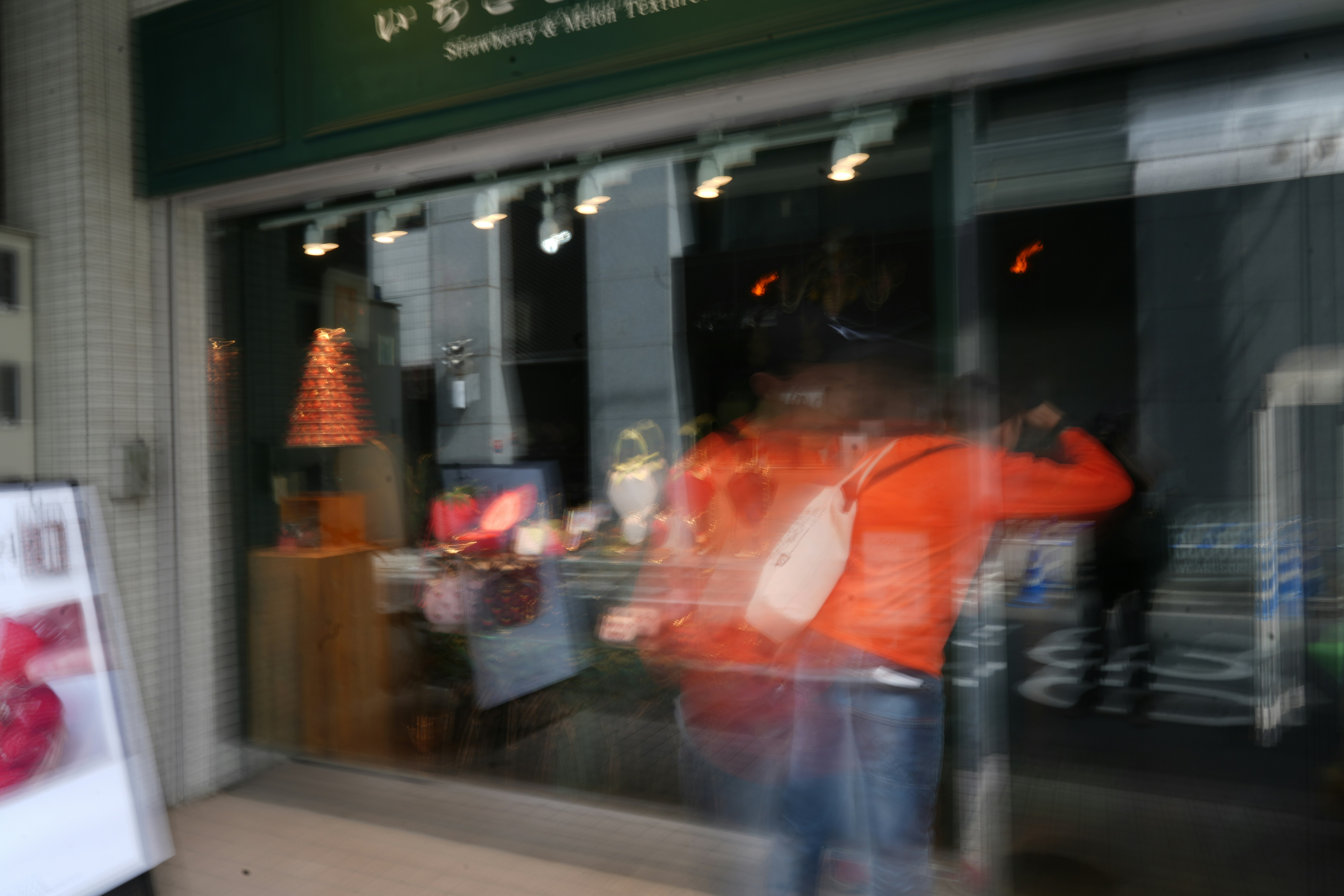 A blurry person is walking past a store.