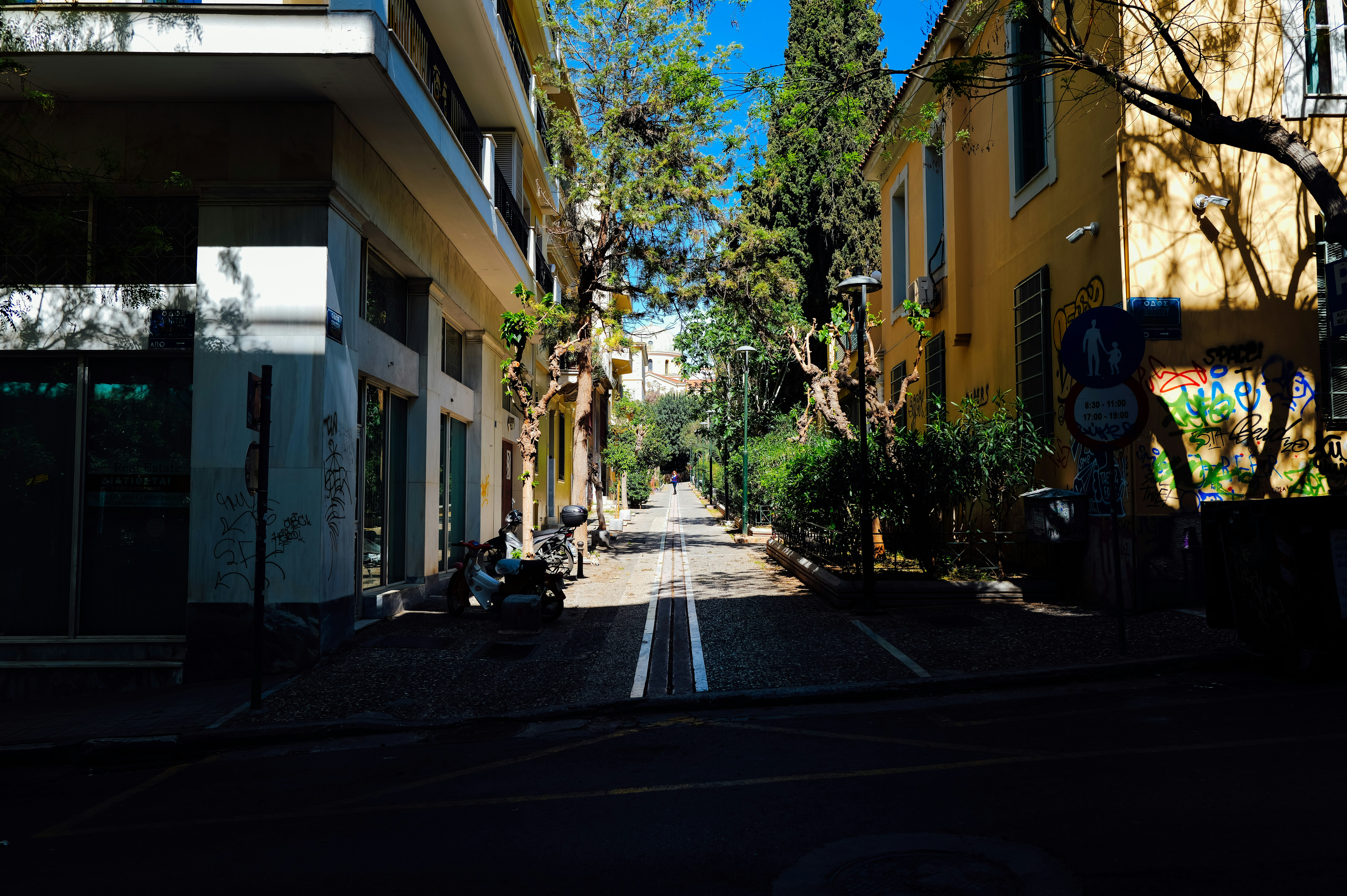 A narrow street between buildings with trees.