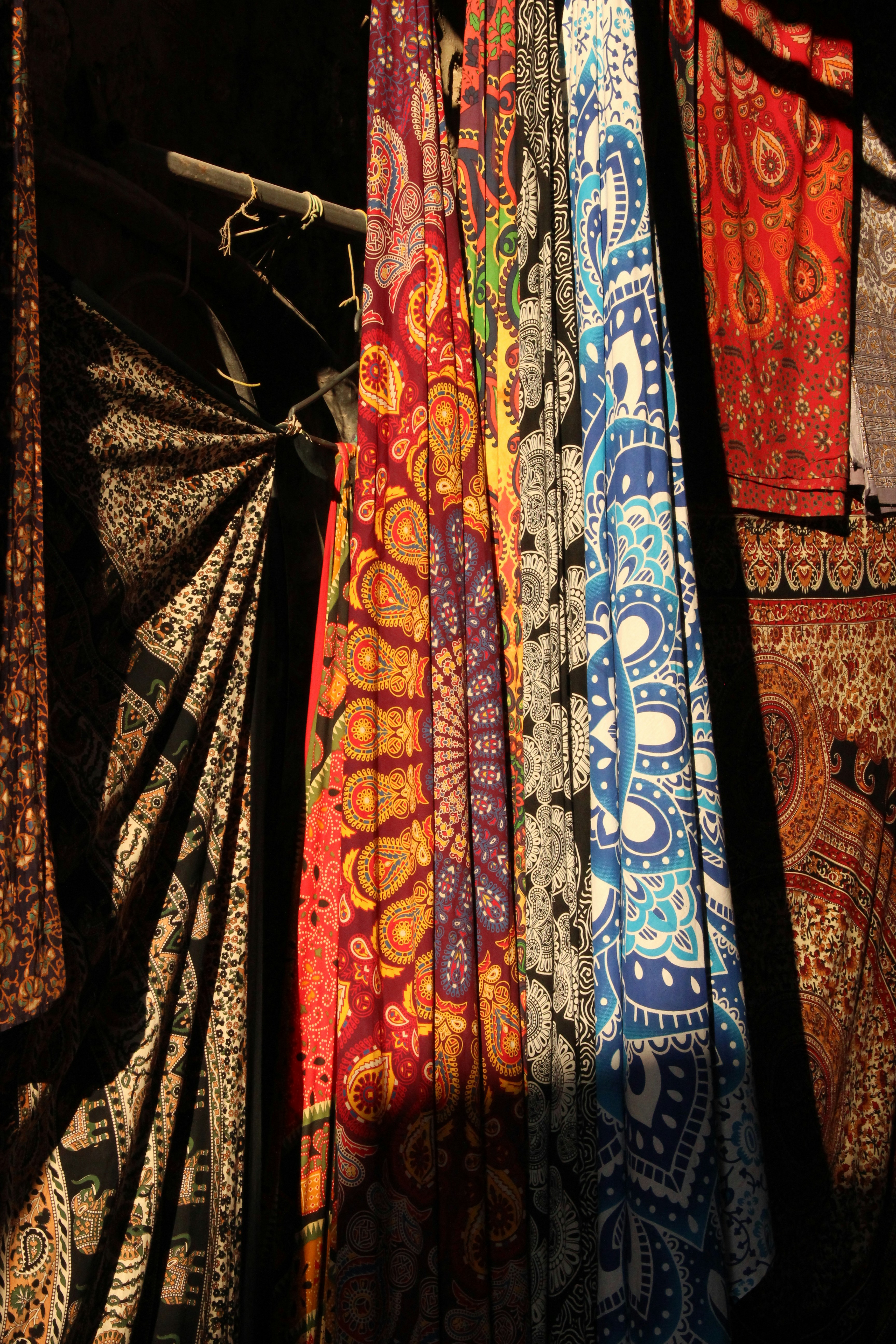 Colorful patterned fabrics hang on display.