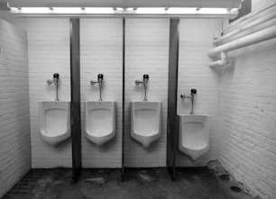 Four urinals stand side-by-side in a restroom
