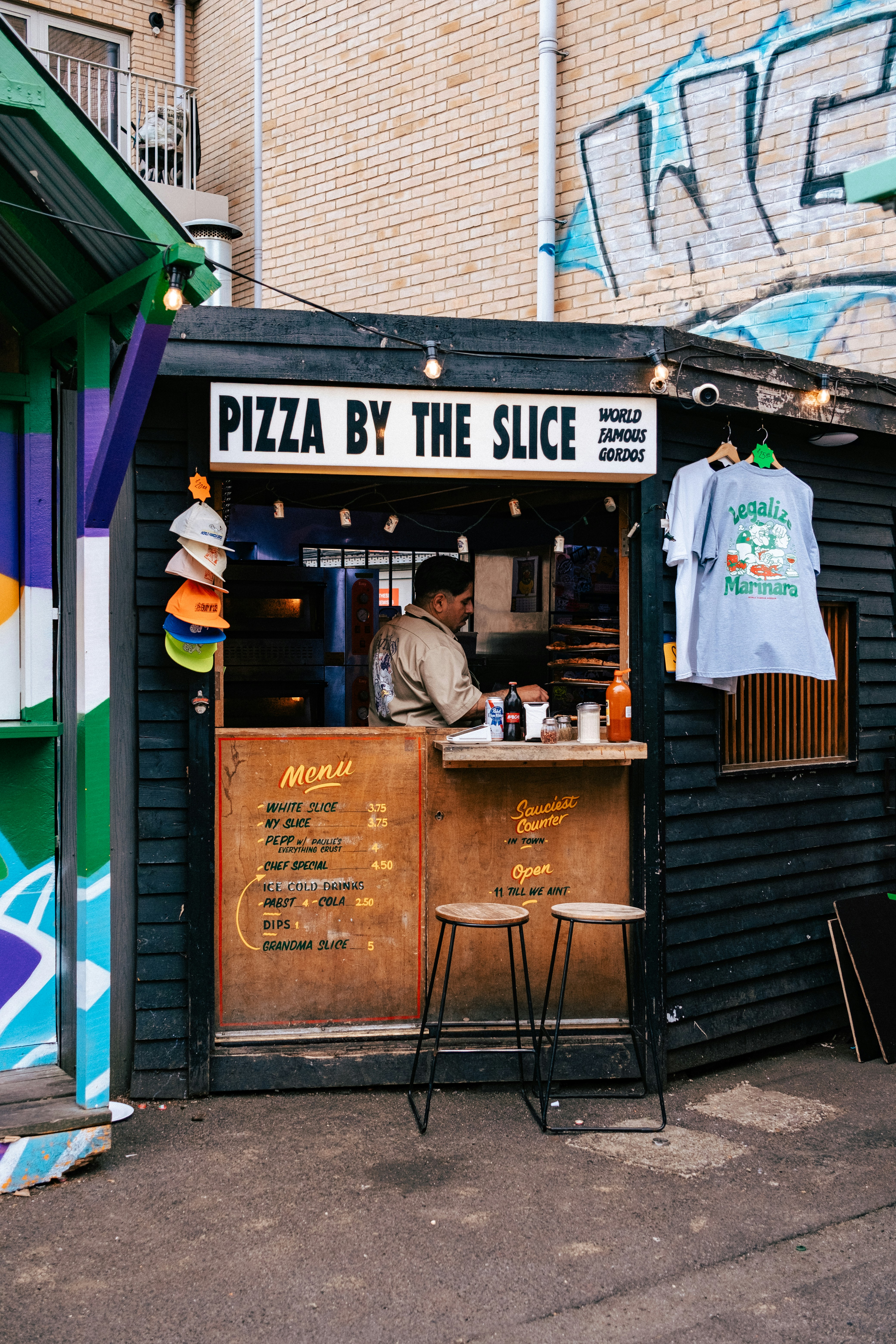 A pizza by the slice vendor is preparing food.