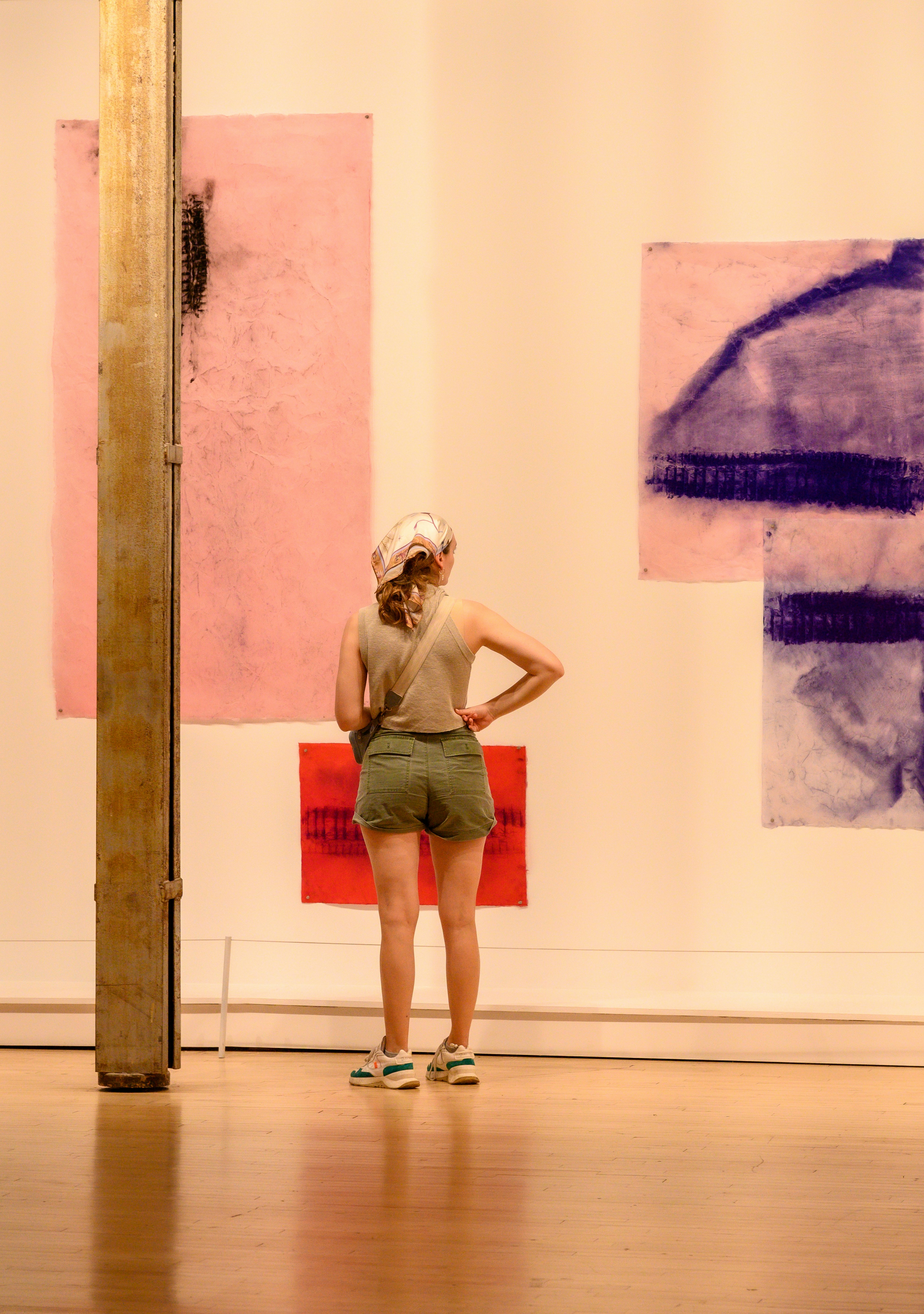 Woman gazes at abstract art in a gallery.