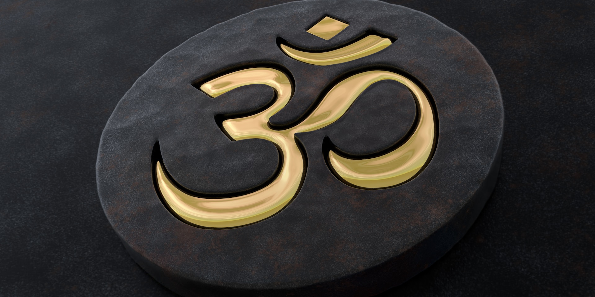 A golden om symbol on a dark stone.