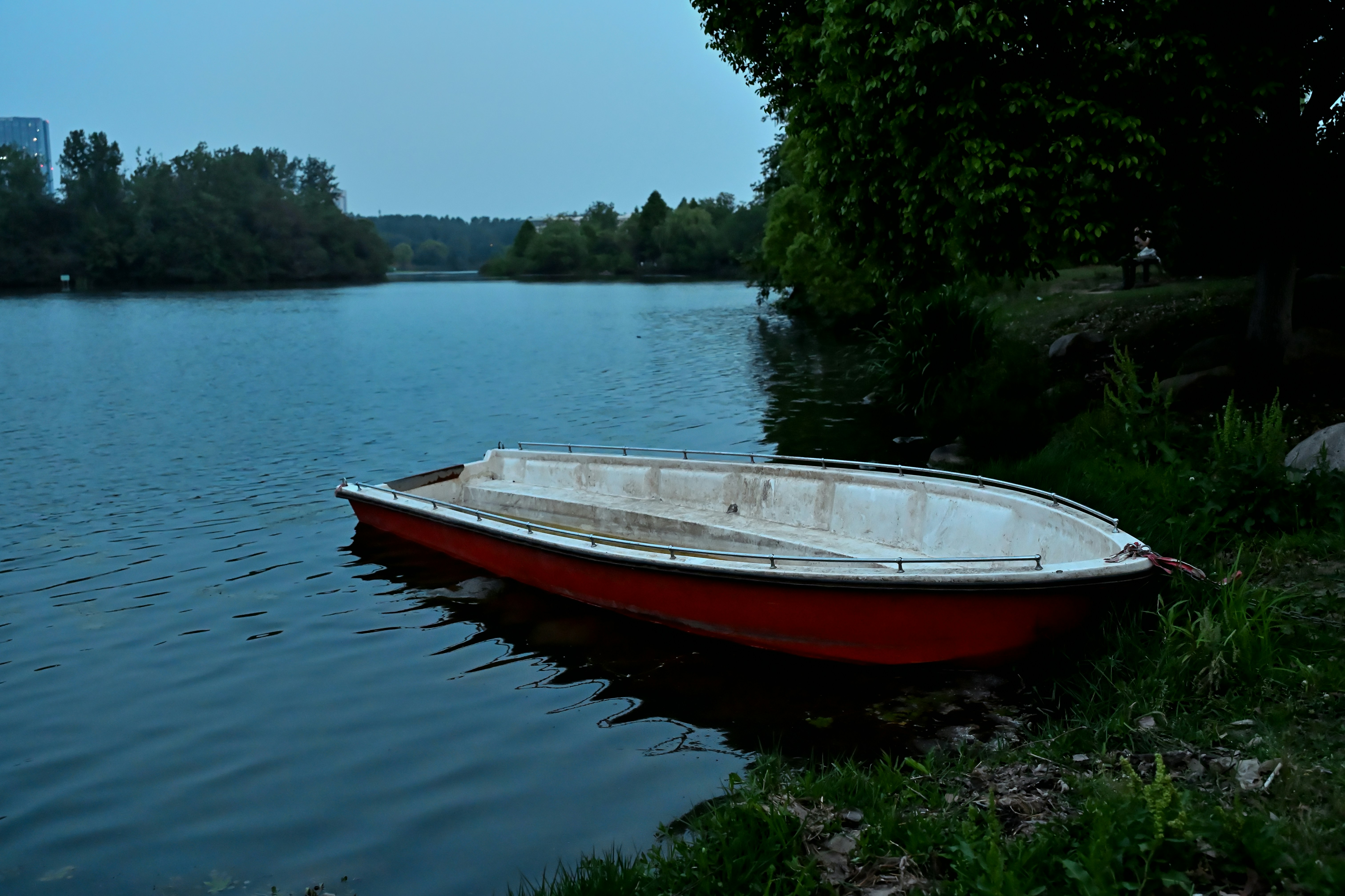 A red boat rests beside still water.