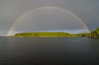 A rainbow arches over the island and water.