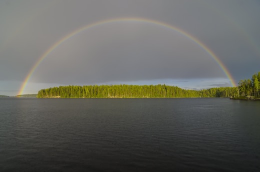 A rainbow arches over the island and water.