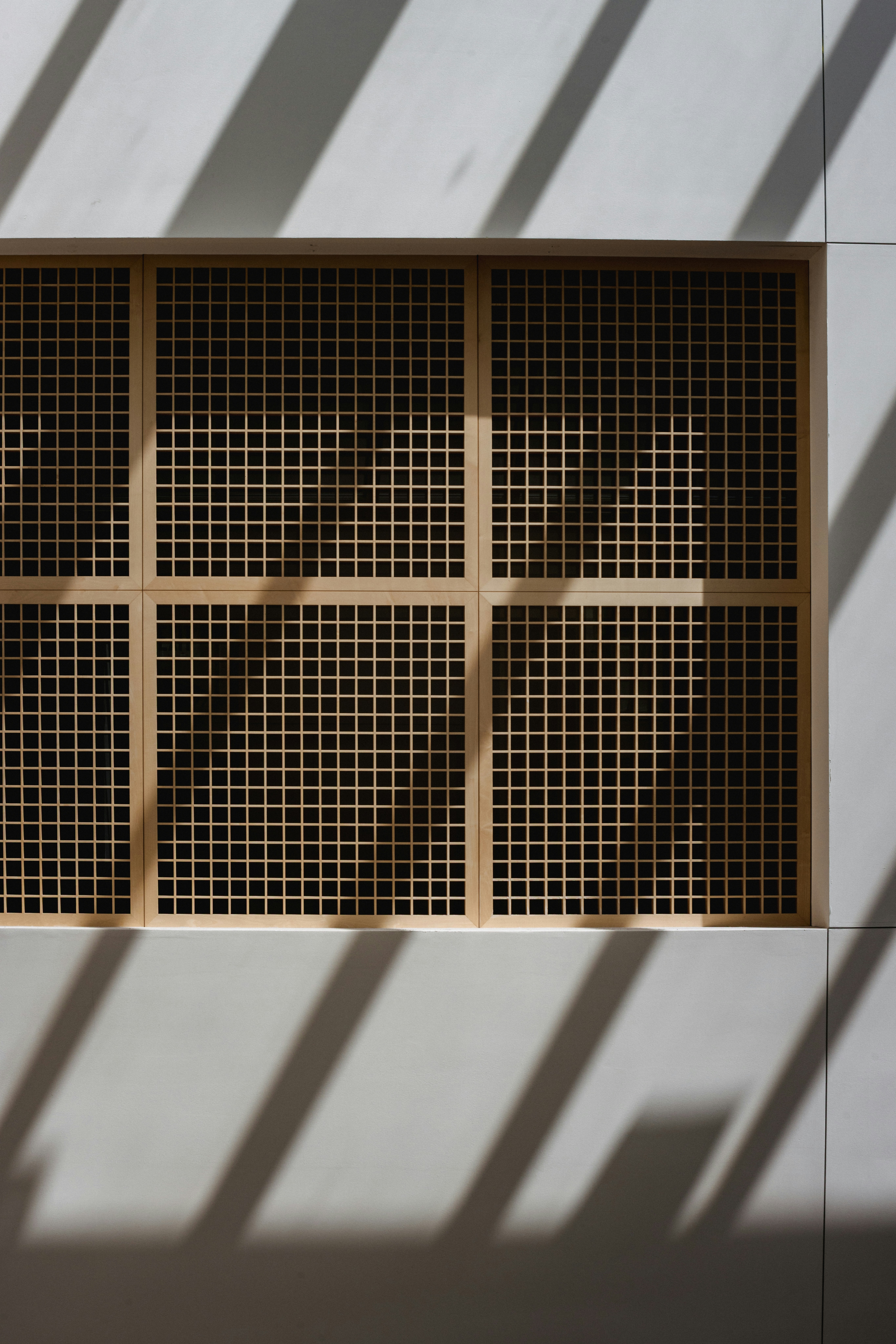 Wooden grid window with sunlight shadows.