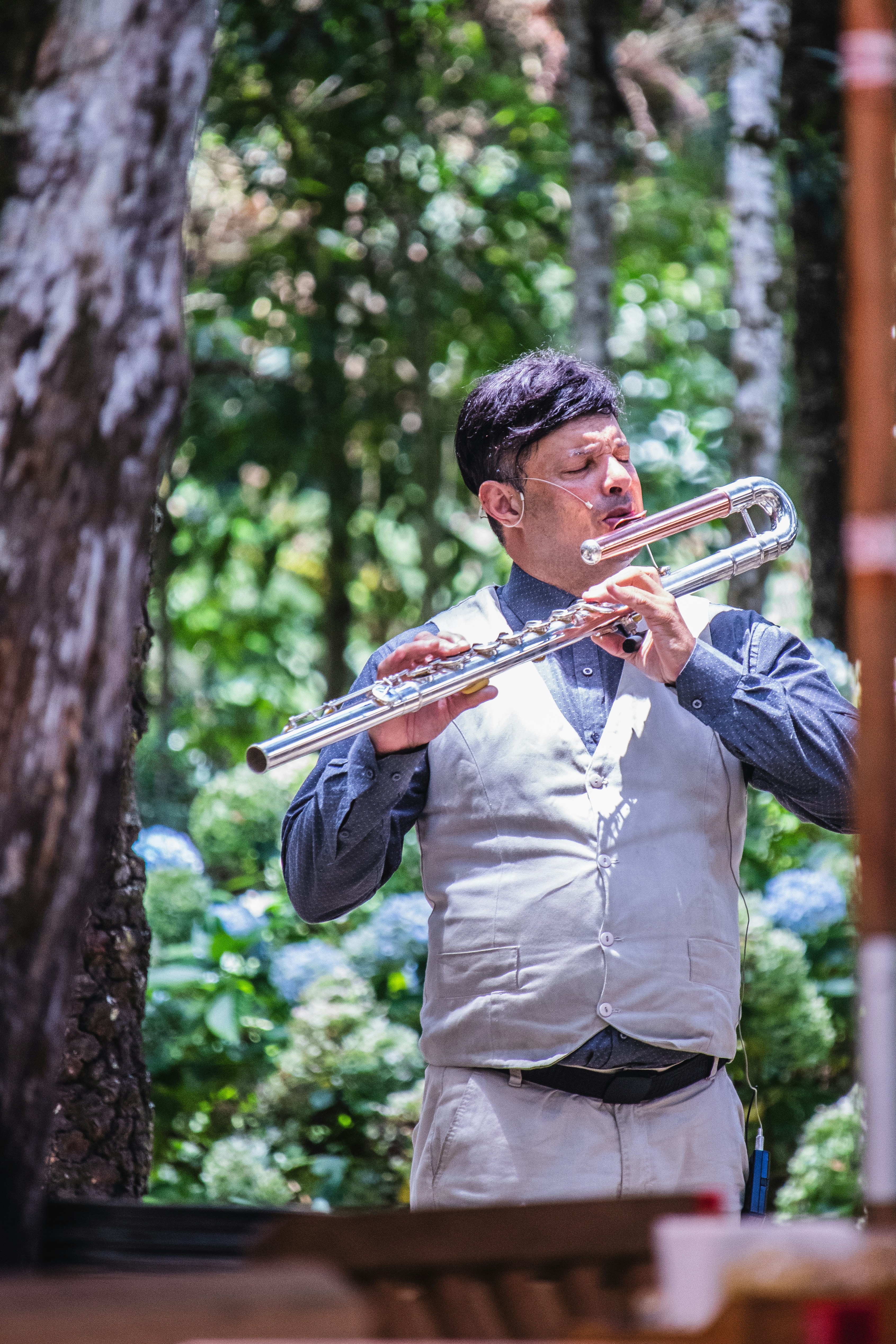 Man plays the flute outside amidst the foliage.