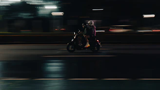 A person rides a scooter at night.