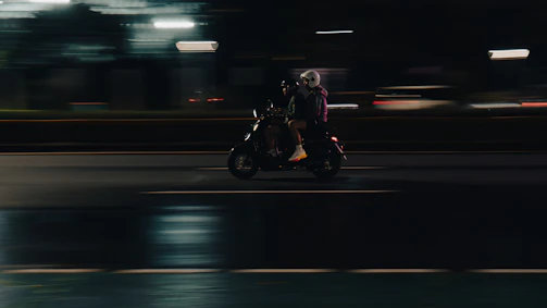 A person rides a scooter at night.