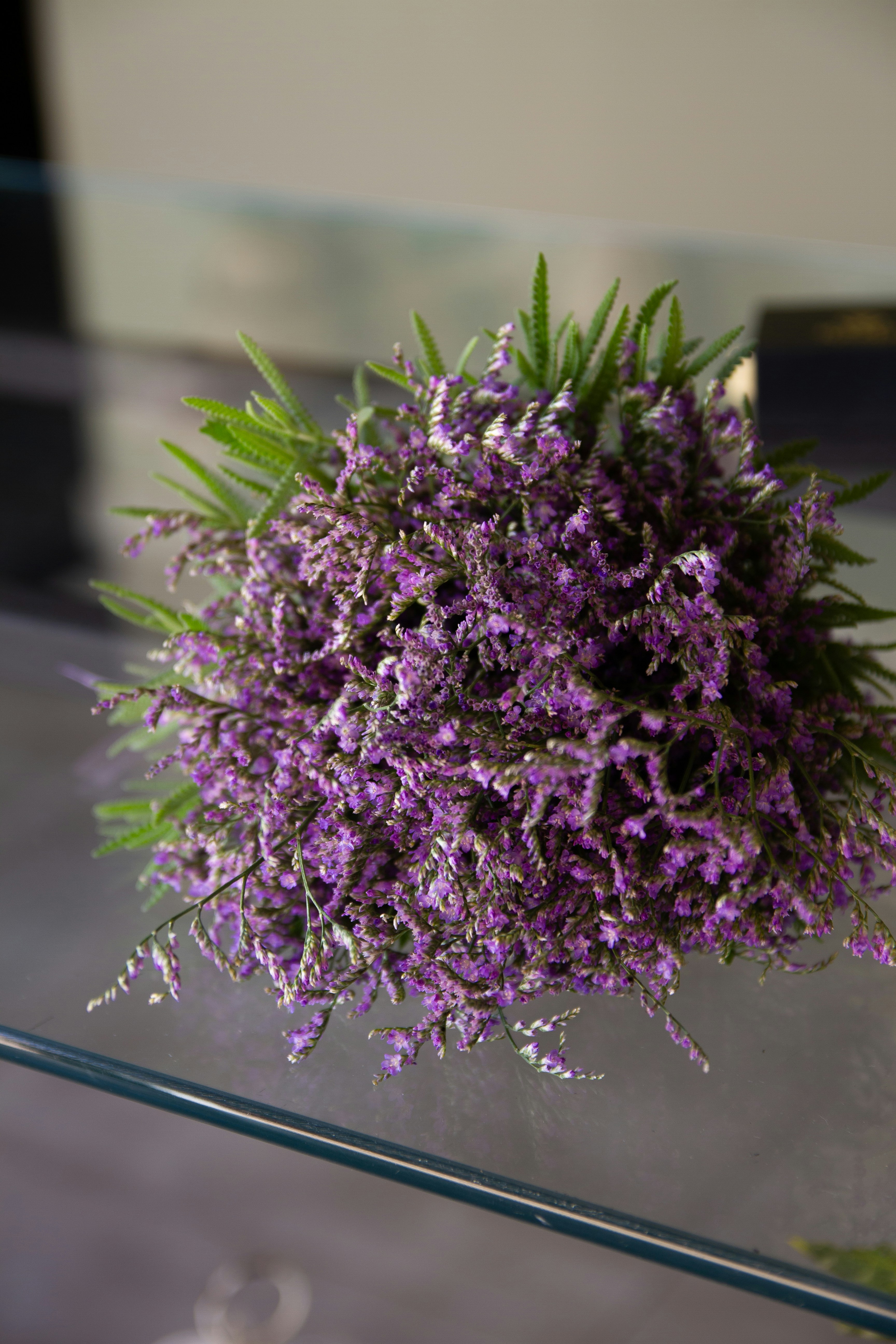A purple bouquet is resting on a glass surface.