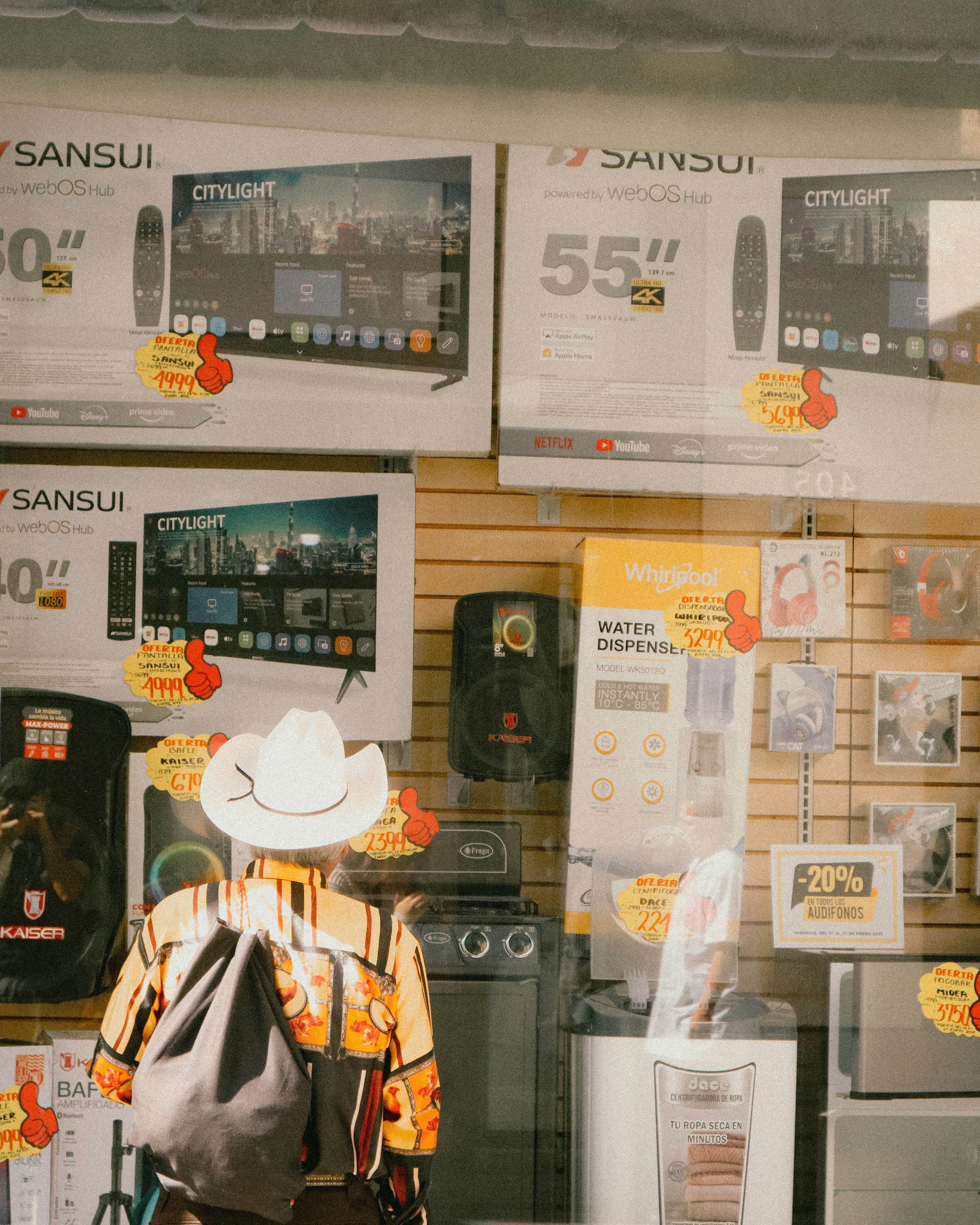 Eine Person schaut sich Fernsehgeräte in einem Schaufenster an.