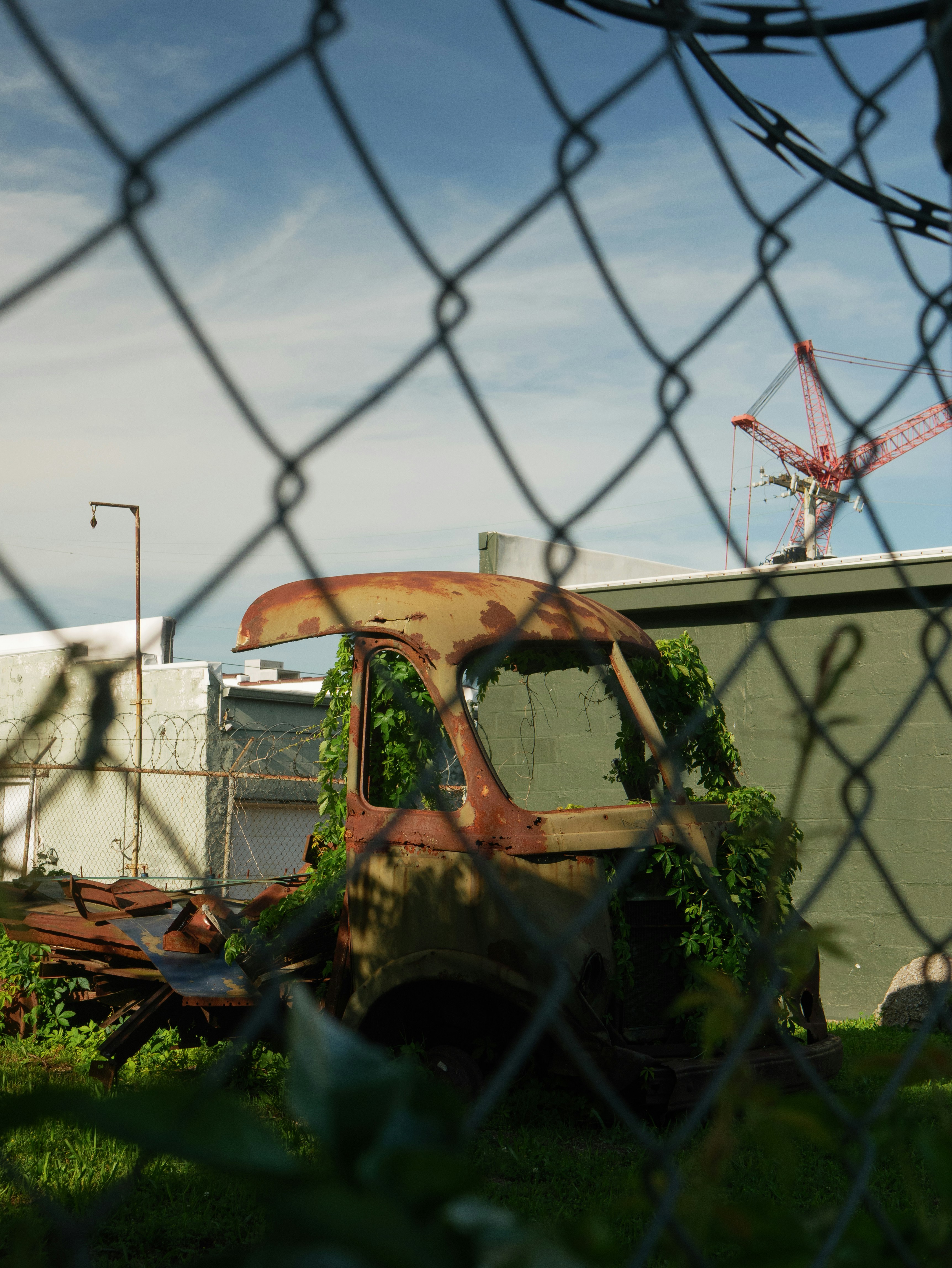Abandoned truck sits behind a chain link fence.