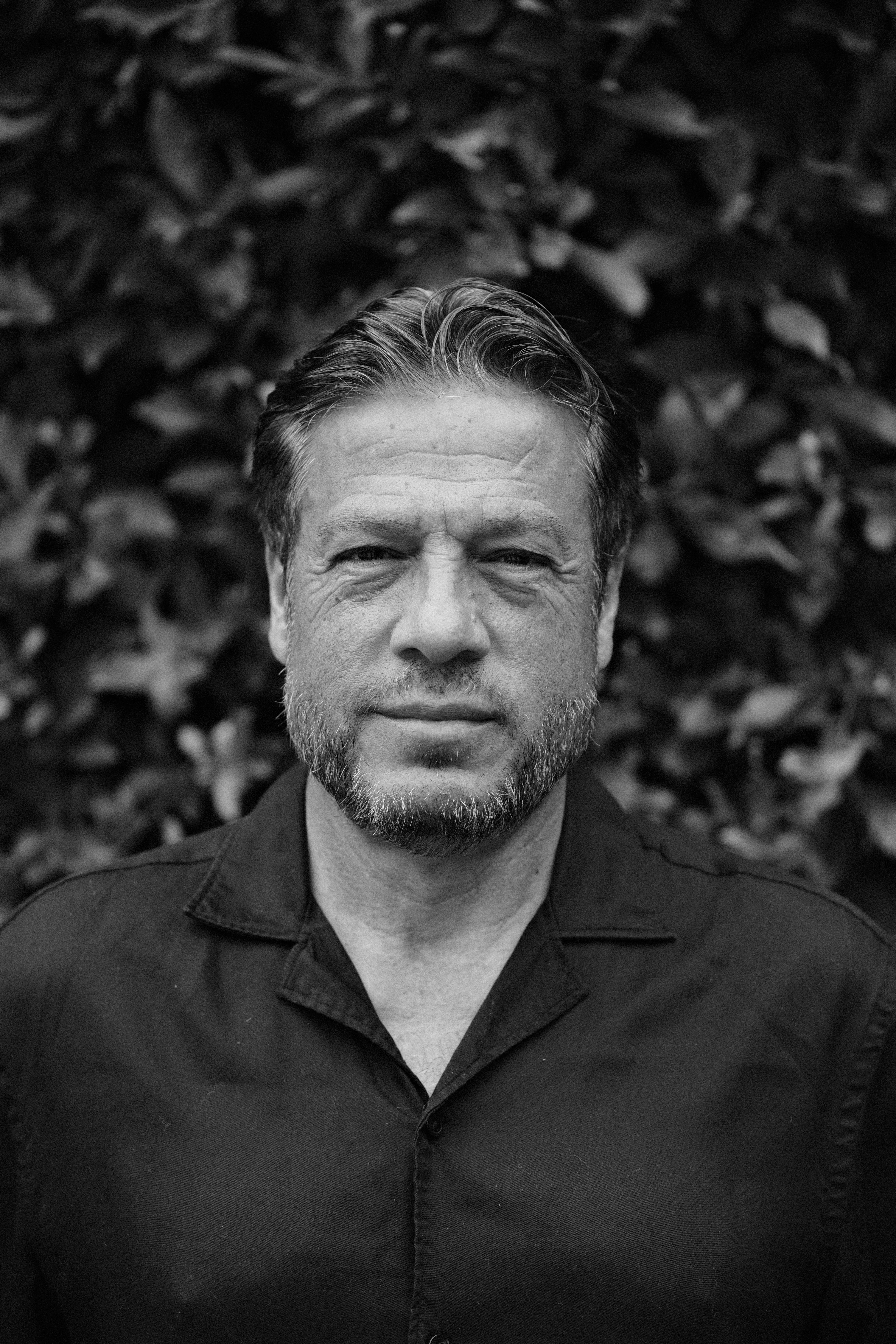 木々の前でポーズをとっている男性。