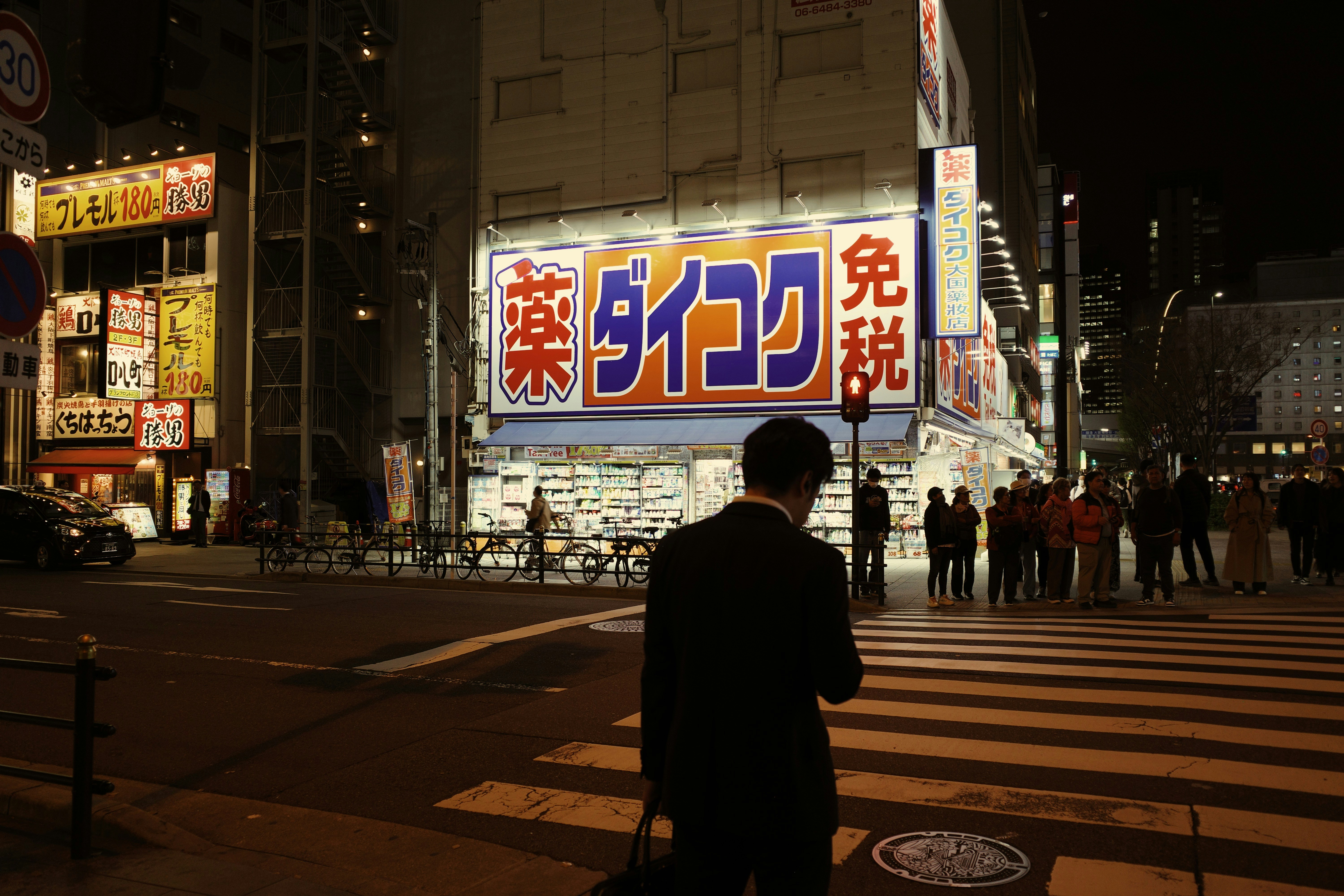 A person crosses the street at night.