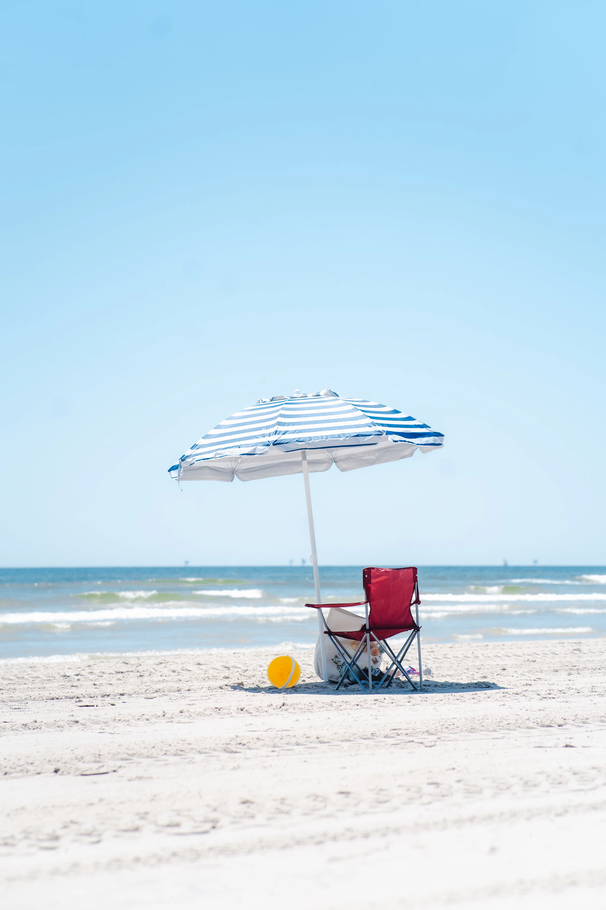 Beach chair and umbrella positioned beside the ocean