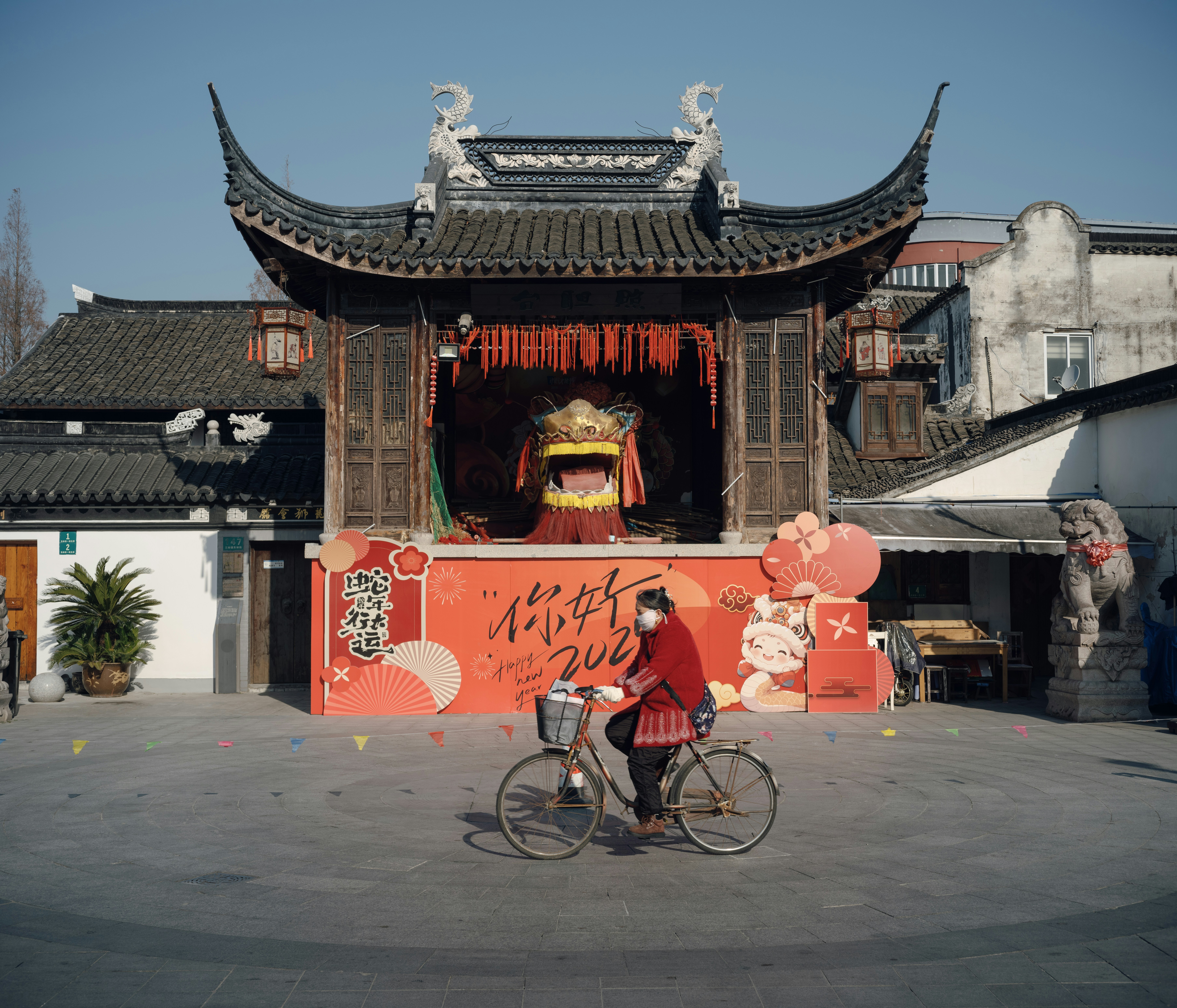 A person cycles past a chinese stage.