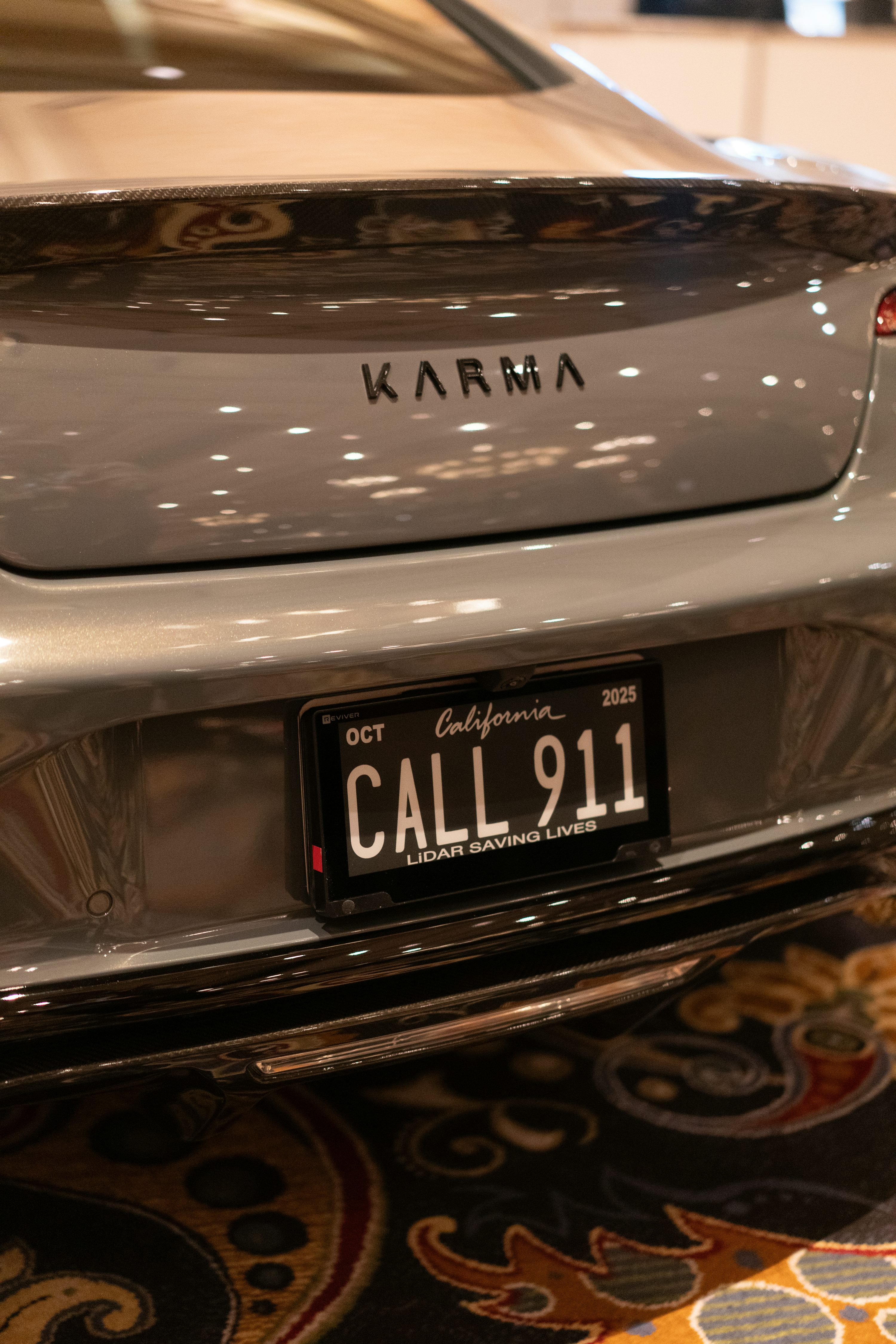 A gray karma car with a funny license plate.