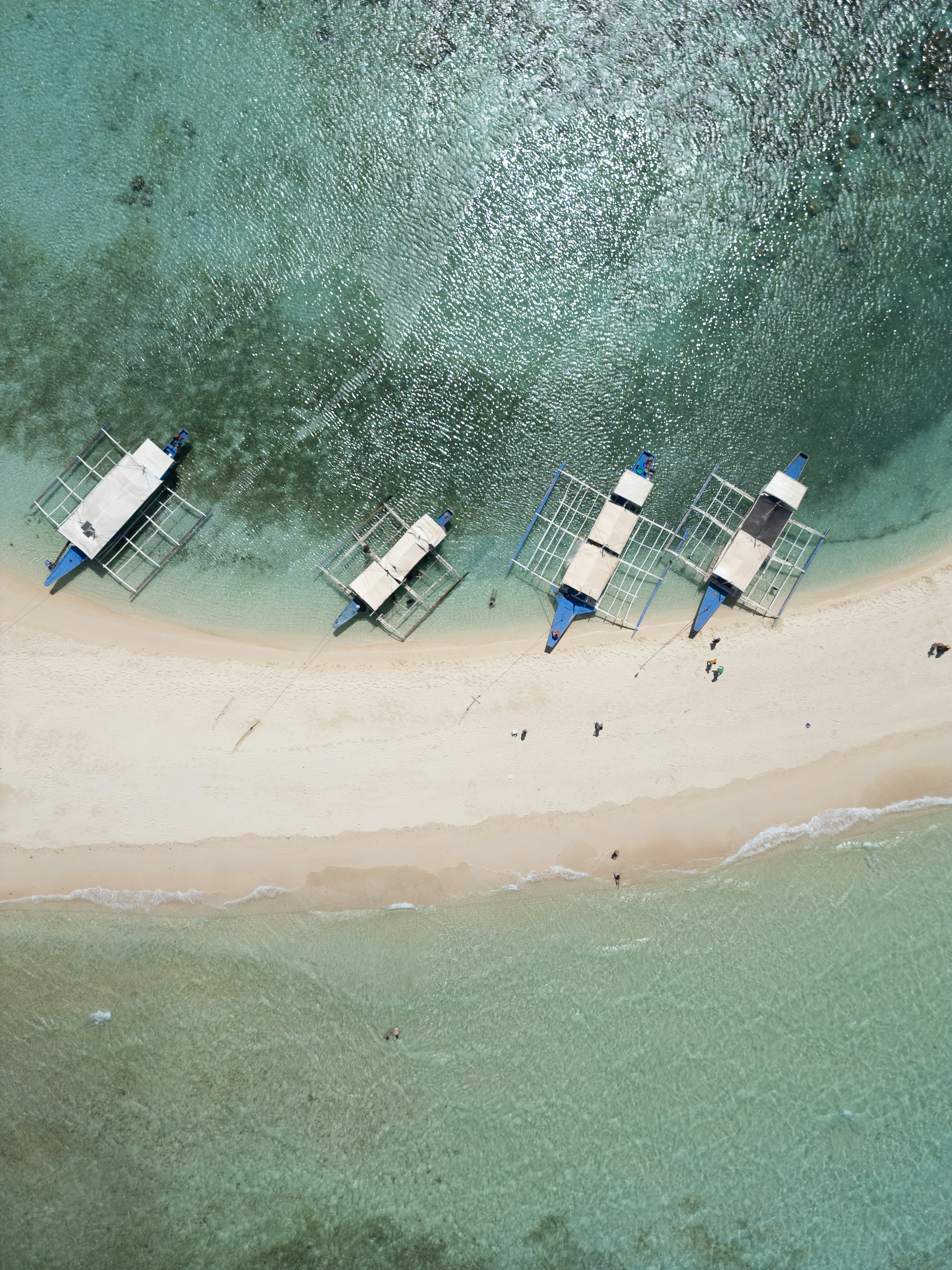 Die Boote liegen auf einer Sandbank in klarem Wasser vor Anker.