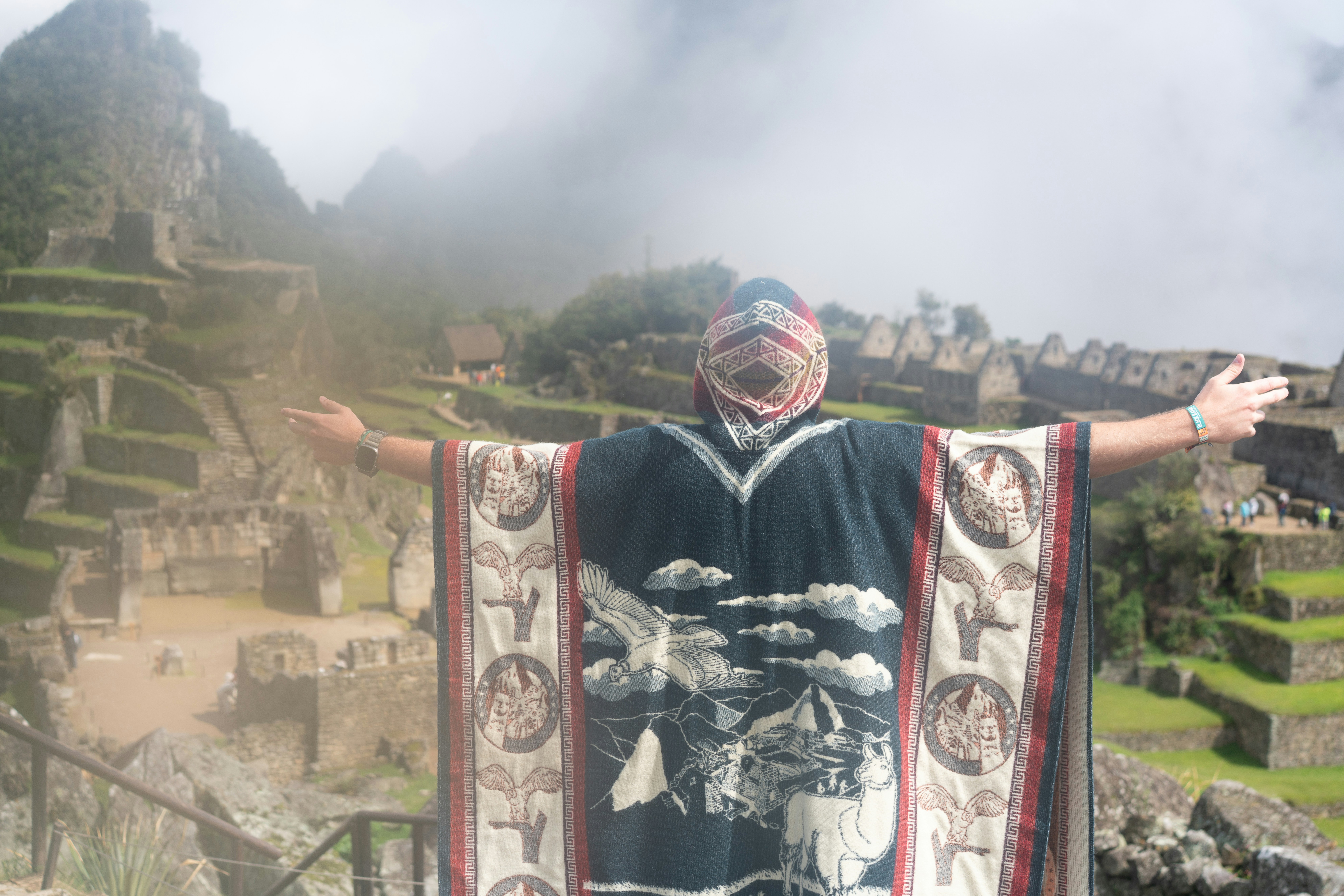 Person vor Machu Picchu mit ausgestreckten Armen.