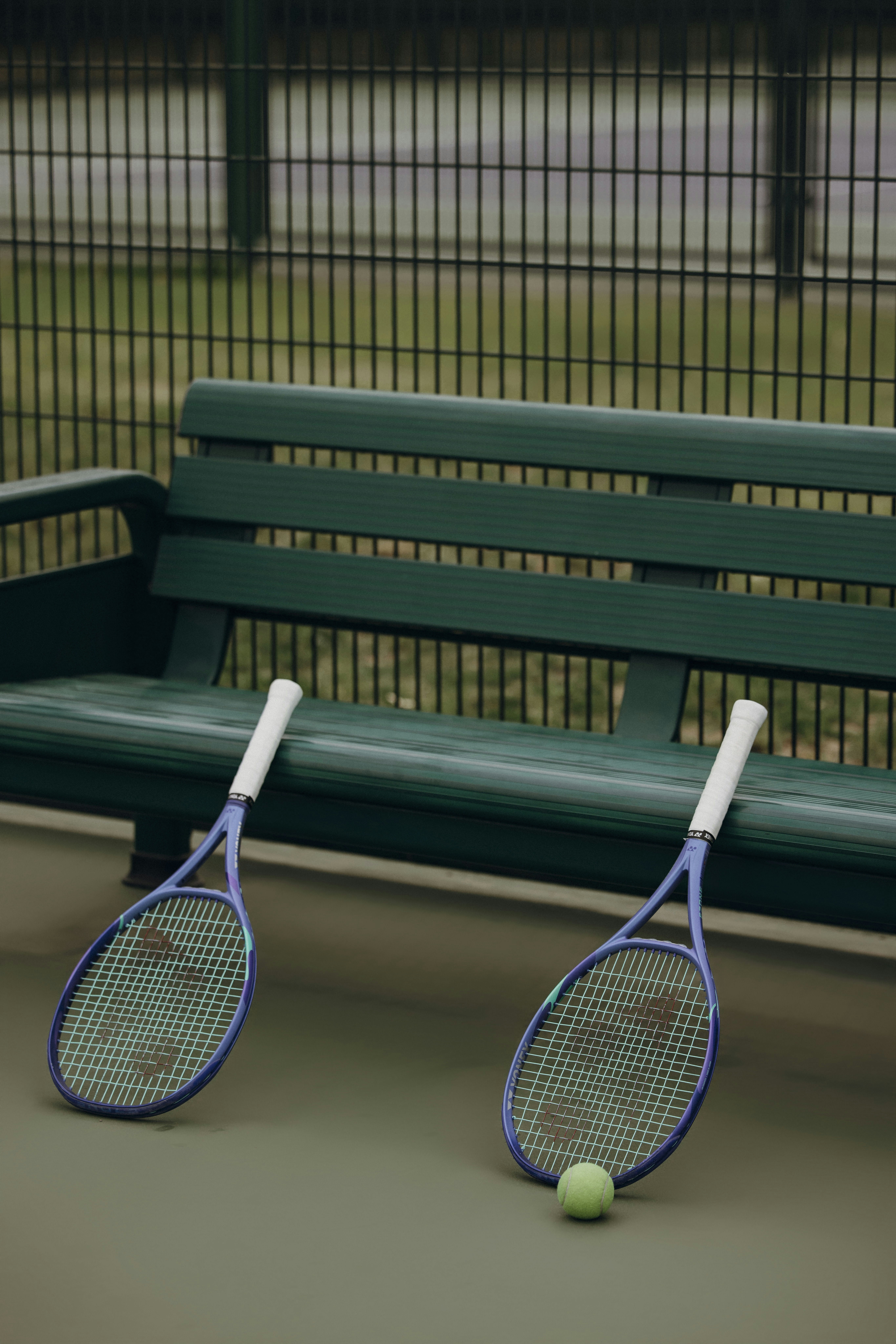 Tennis rackets and a ball rest by a bench.