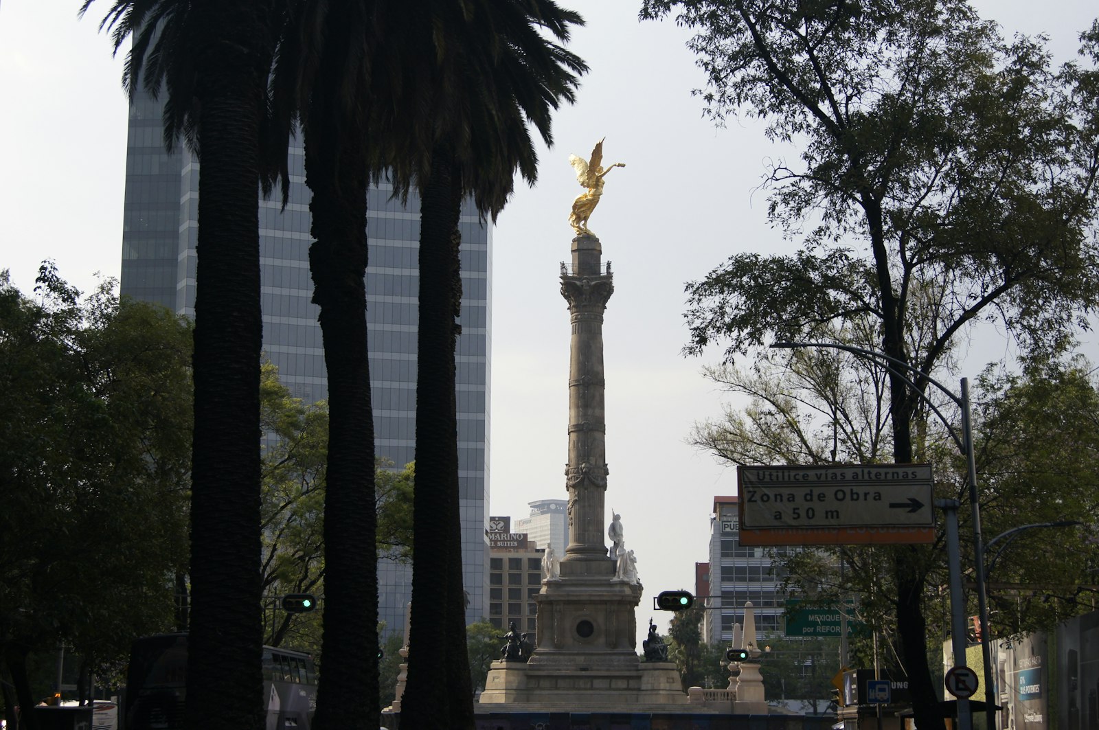 Angel de la Independencia monument on Paseo de la Reforma in Mexico City surrounded by palm trees and modern towers