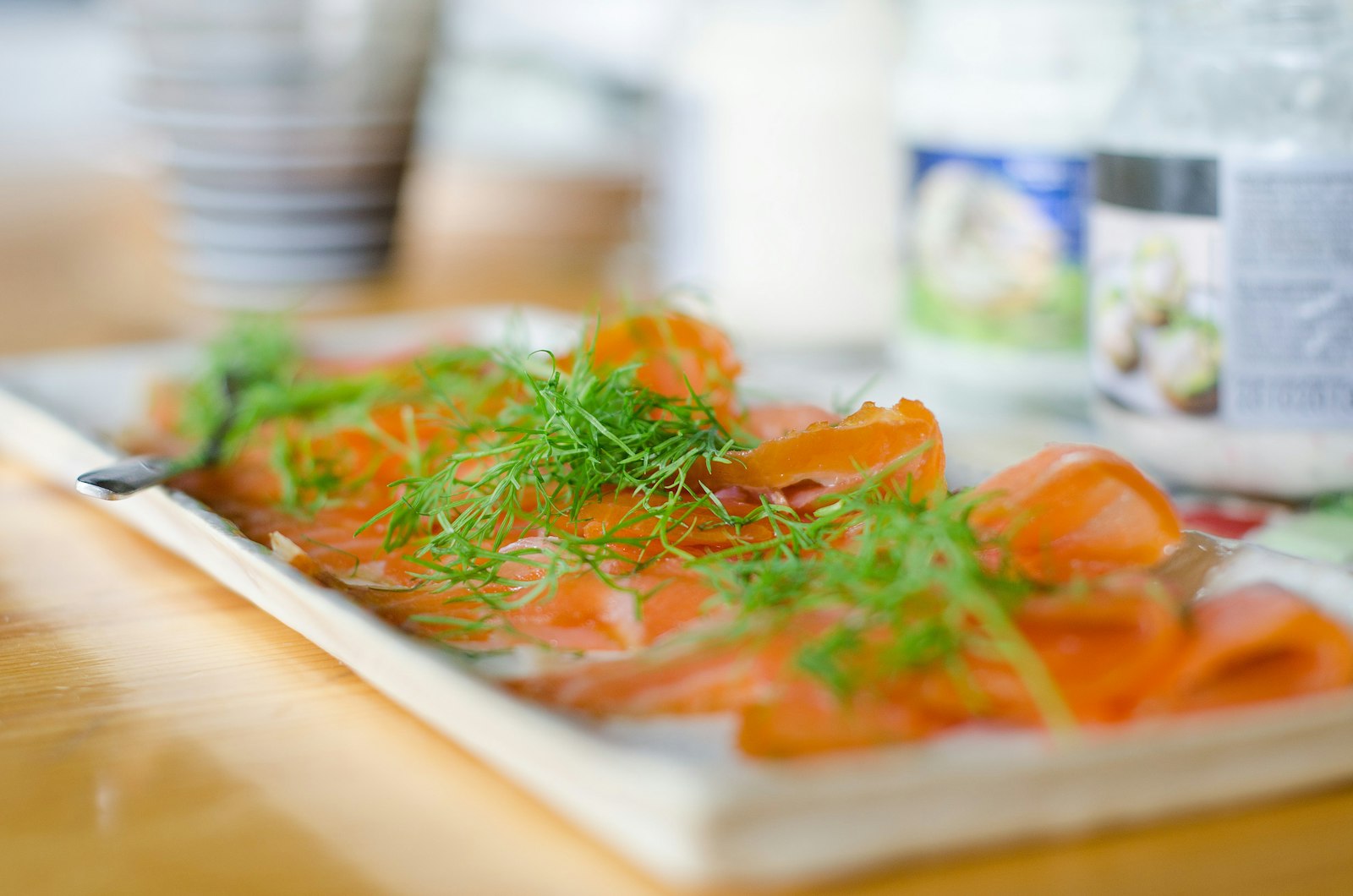 Tynne skiver speket ørret med dill på et hvitt serveringsfat