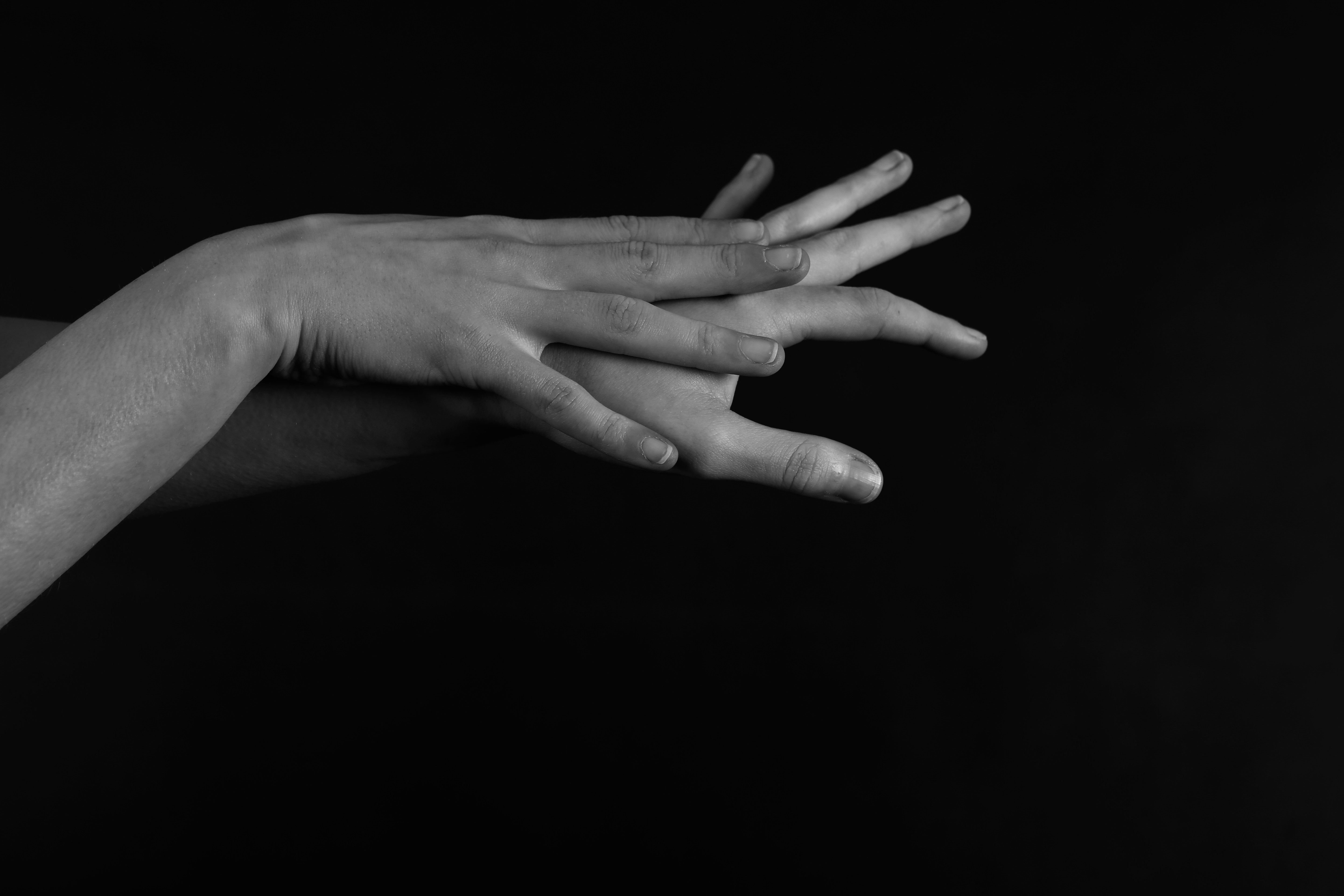 사진 찍을 때 팔 길어 보이는 포즈 - Hands intertwine against a dark background.