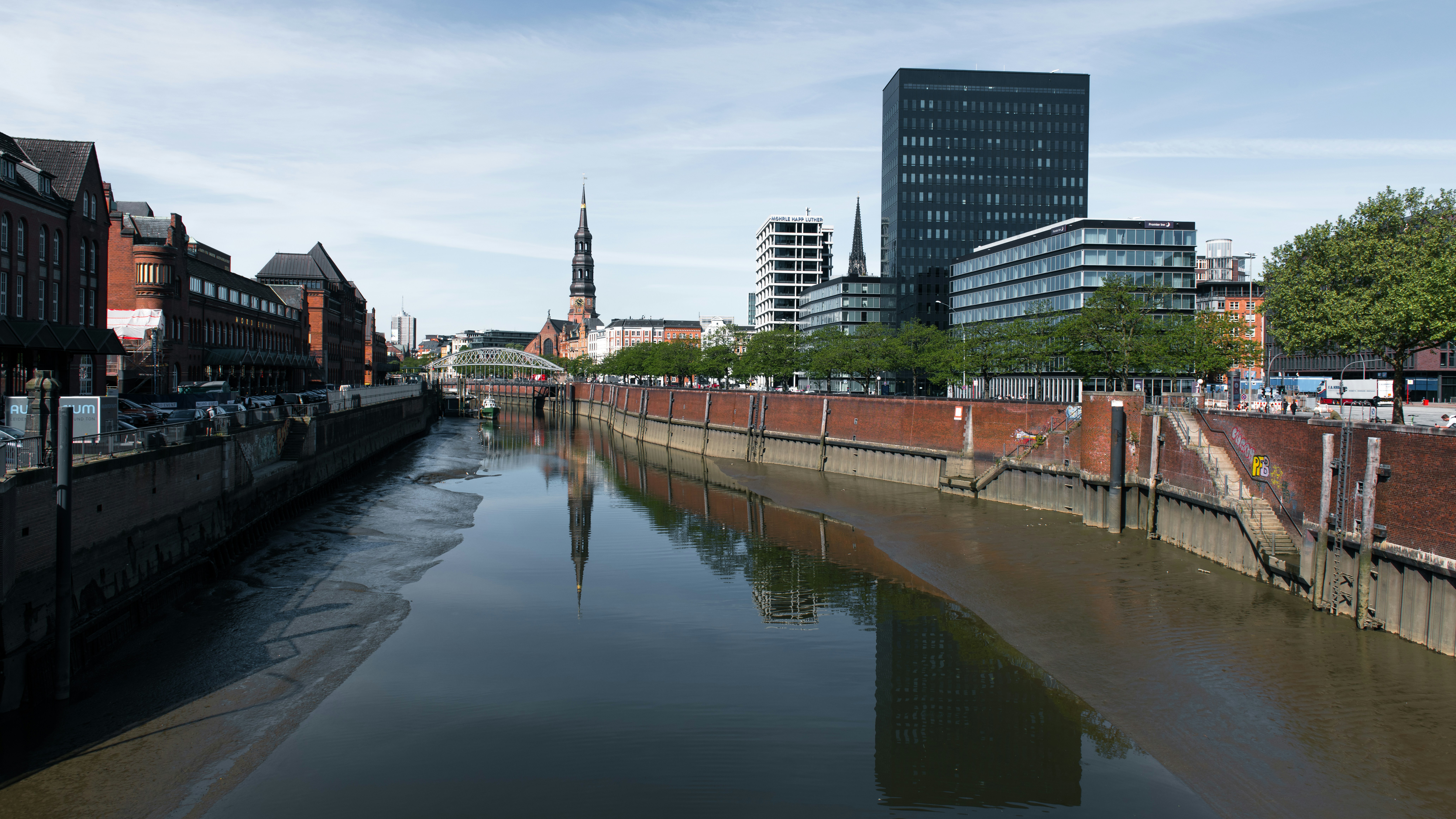 A canal flows through a city under a cloudy sky.