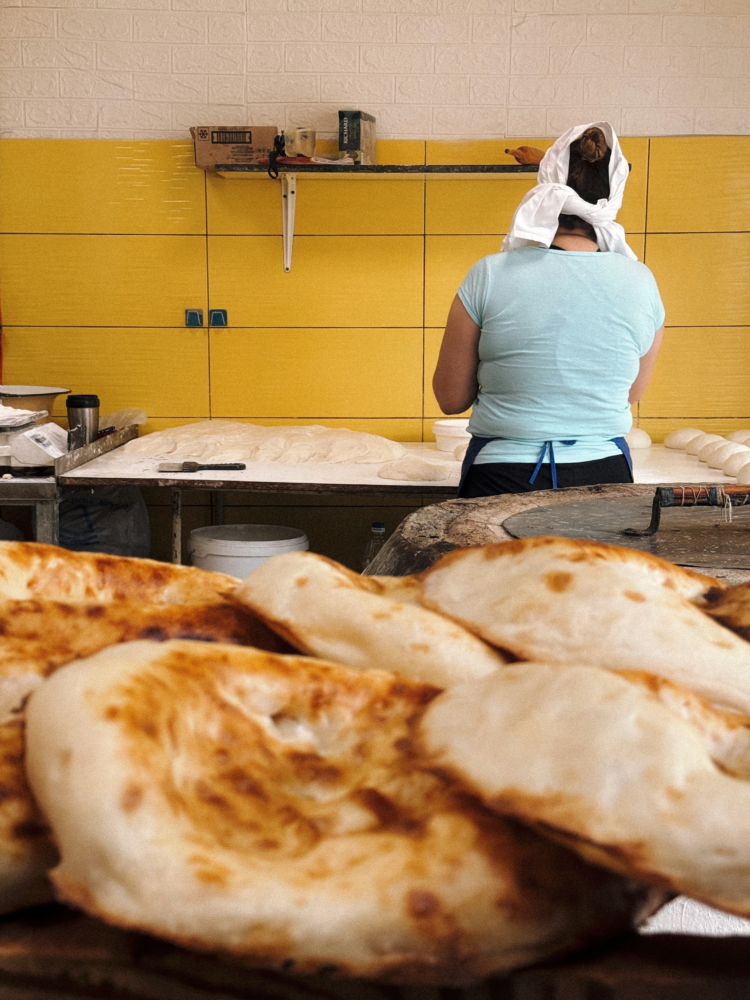 Freshly baked bread sits while baker works.