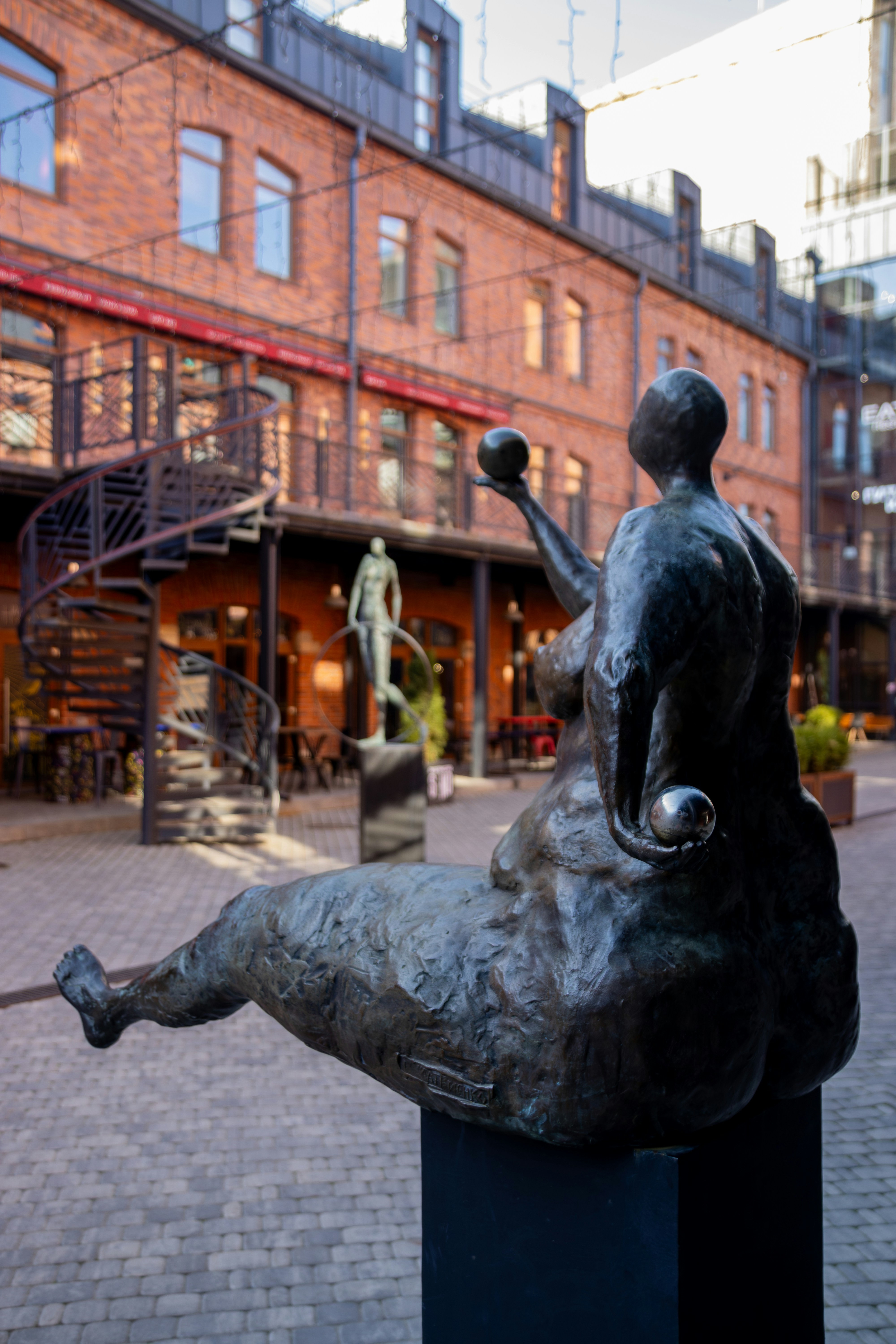 A bronze sculpture rests in a brick-lined courtyard.