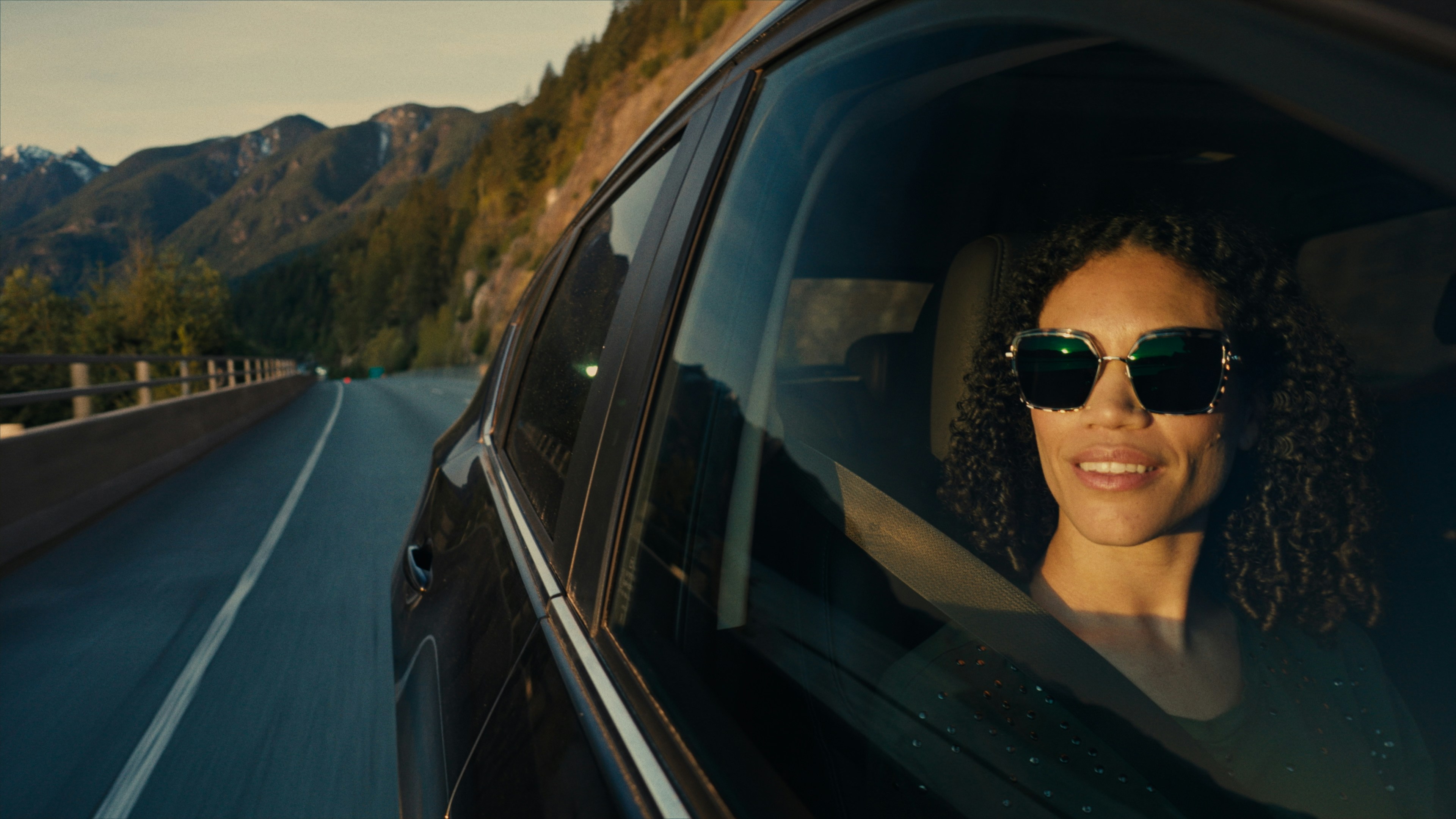 A woman in a car enjoys the scenic drive.