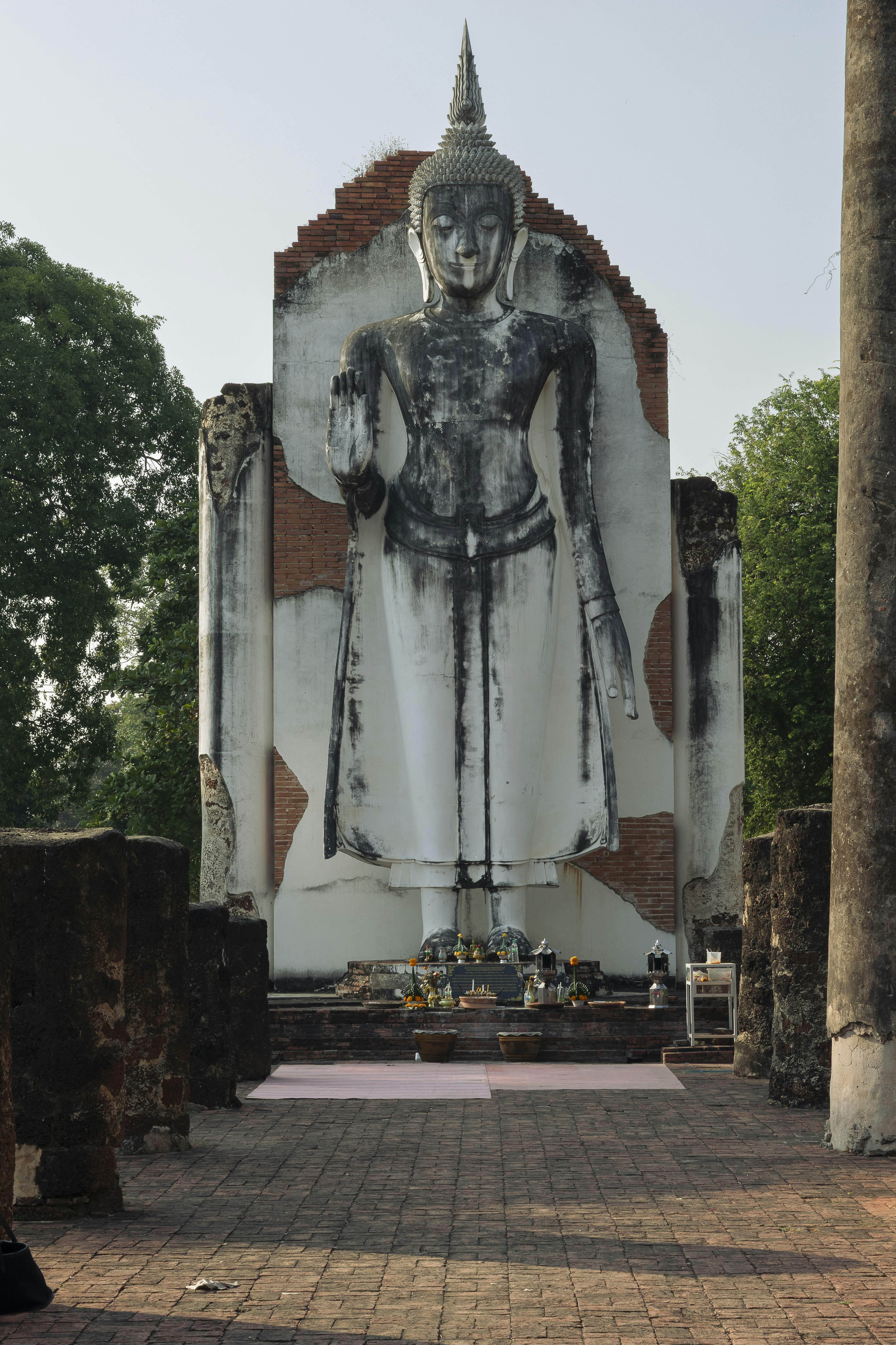 A towering buddha statue in a damaged structure.