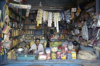 A man smiles in a packed, open-front store.