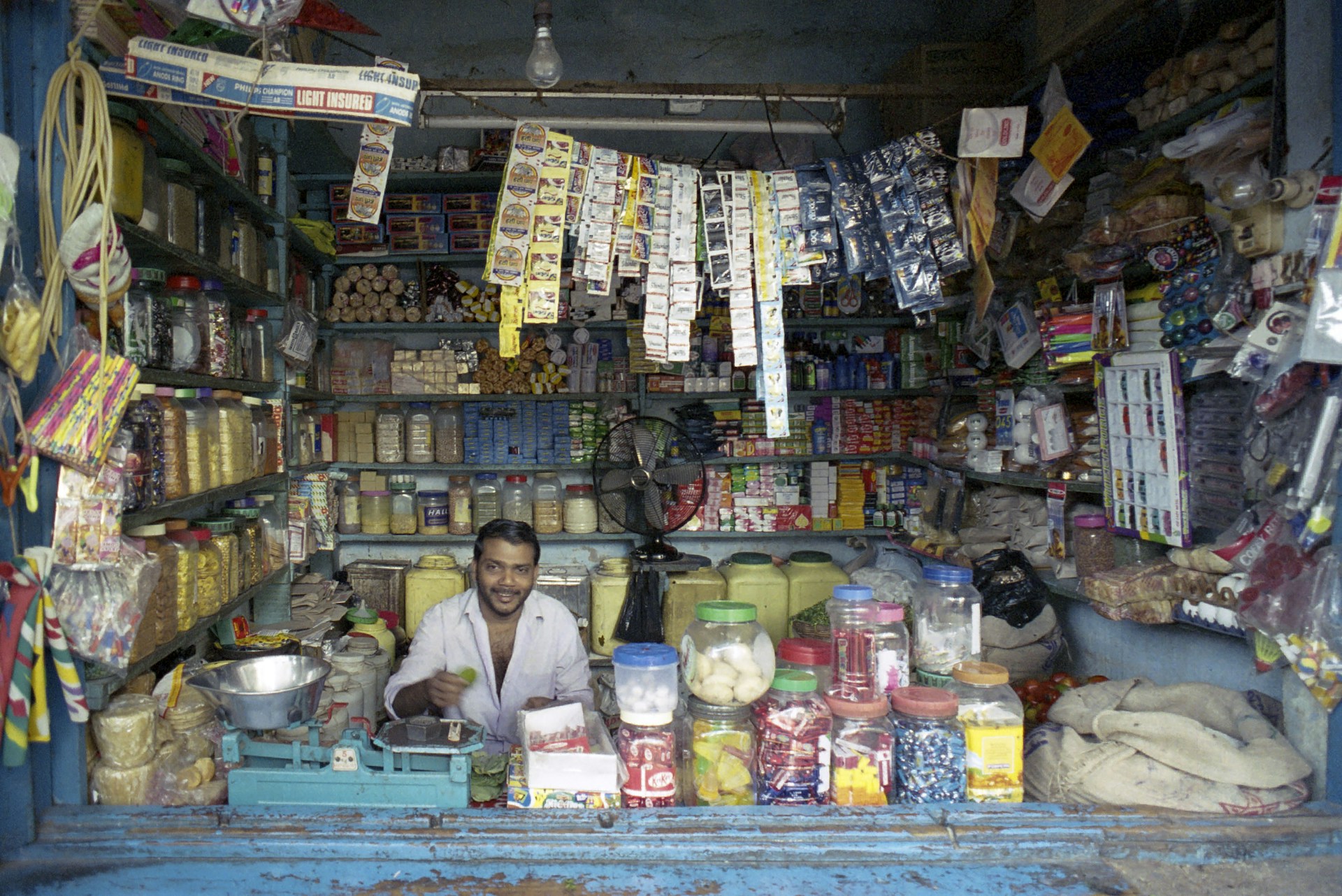 A man smiles in a packed, open-front store.