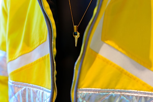 A gold necklace worn over a yellow jacket.