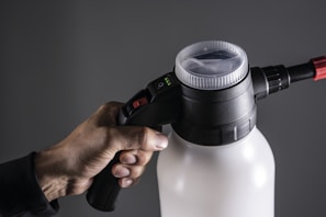 Hand holding a white and black spray bottle.