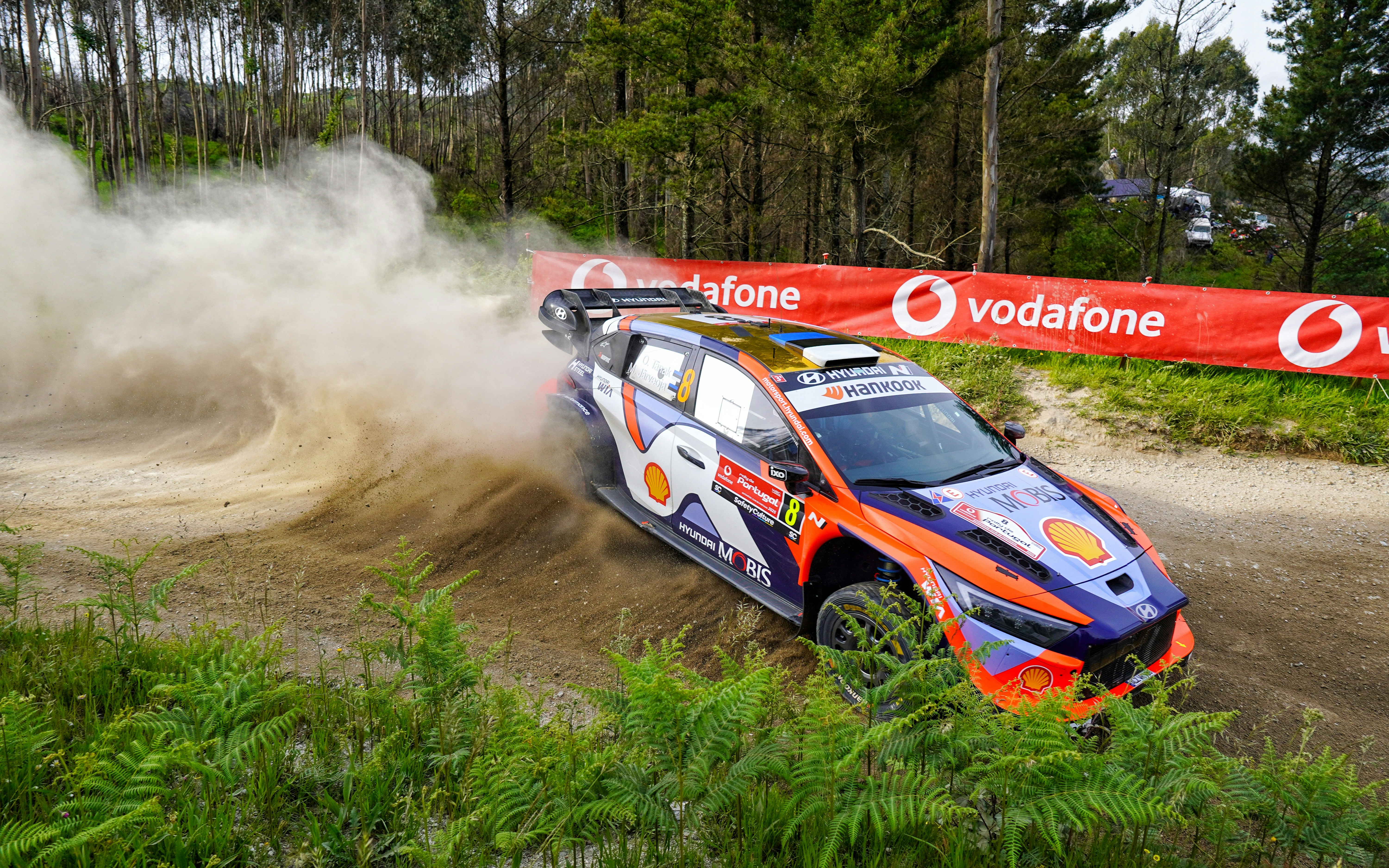A rally car speeds down a dusty road.