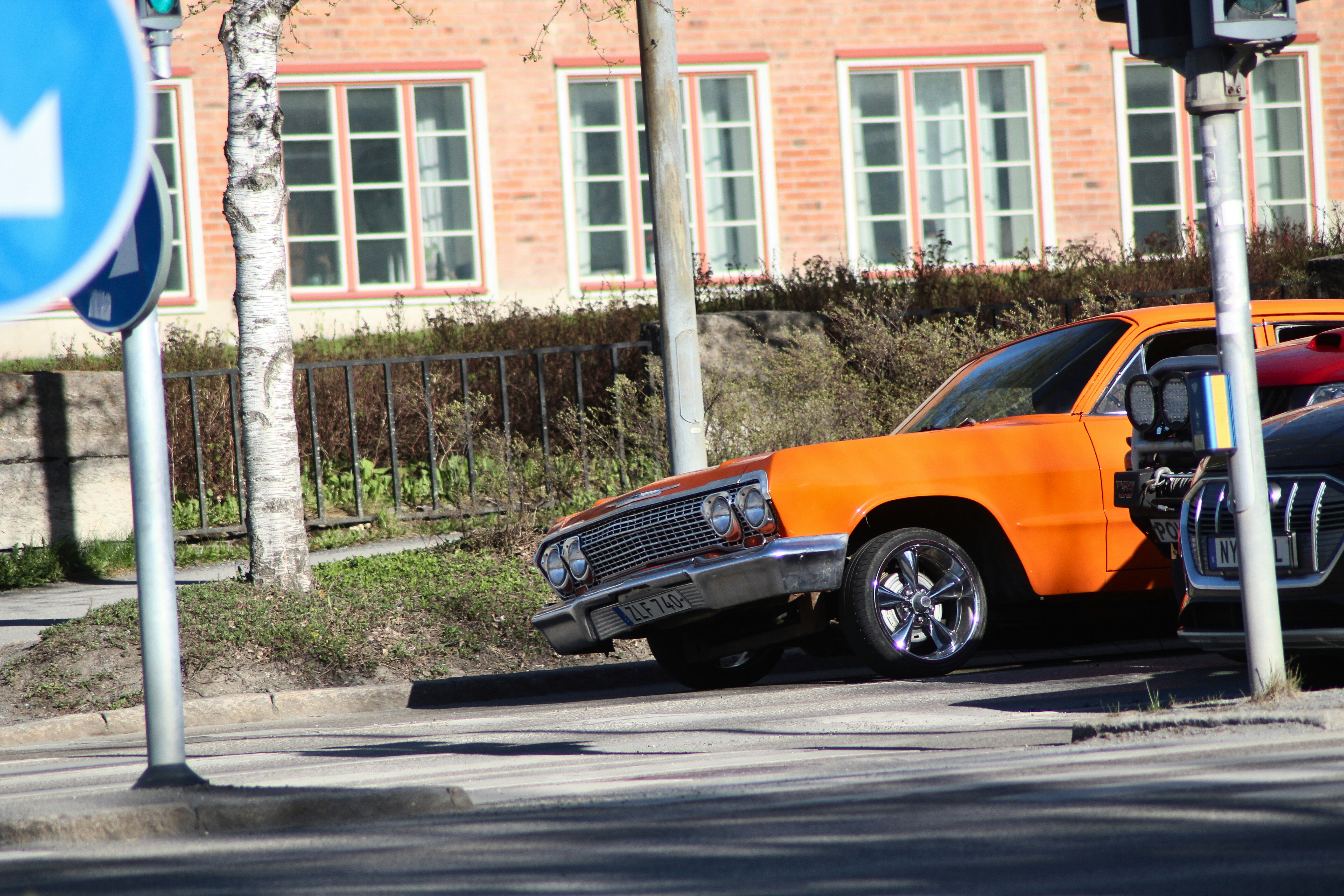 Orange car parked near a street sign.