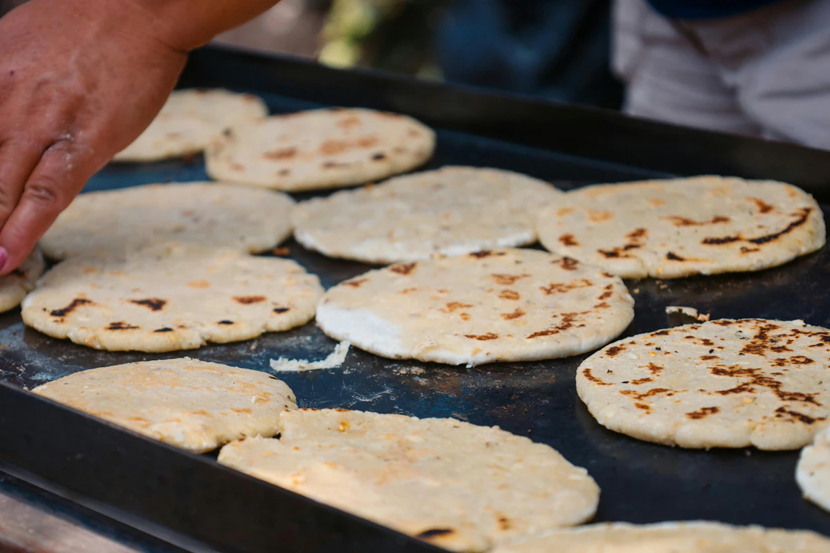 Pupusas cooking on a hot griddle
