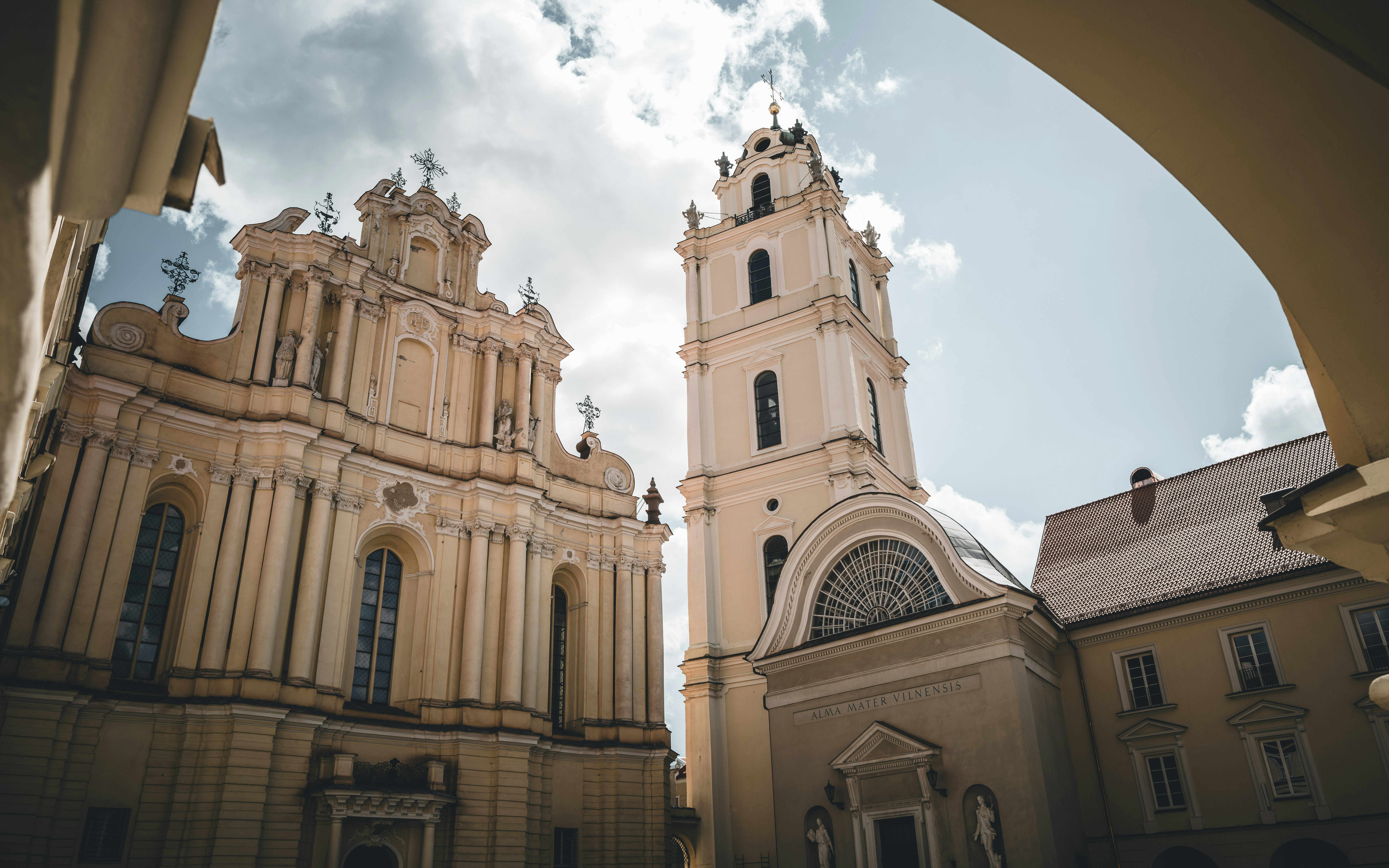 Baroque-style church with ornate facade and tall bell tower under a partly cloudy sky.