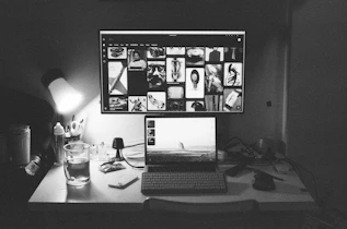 A laptop and monitor display photos on a desk.