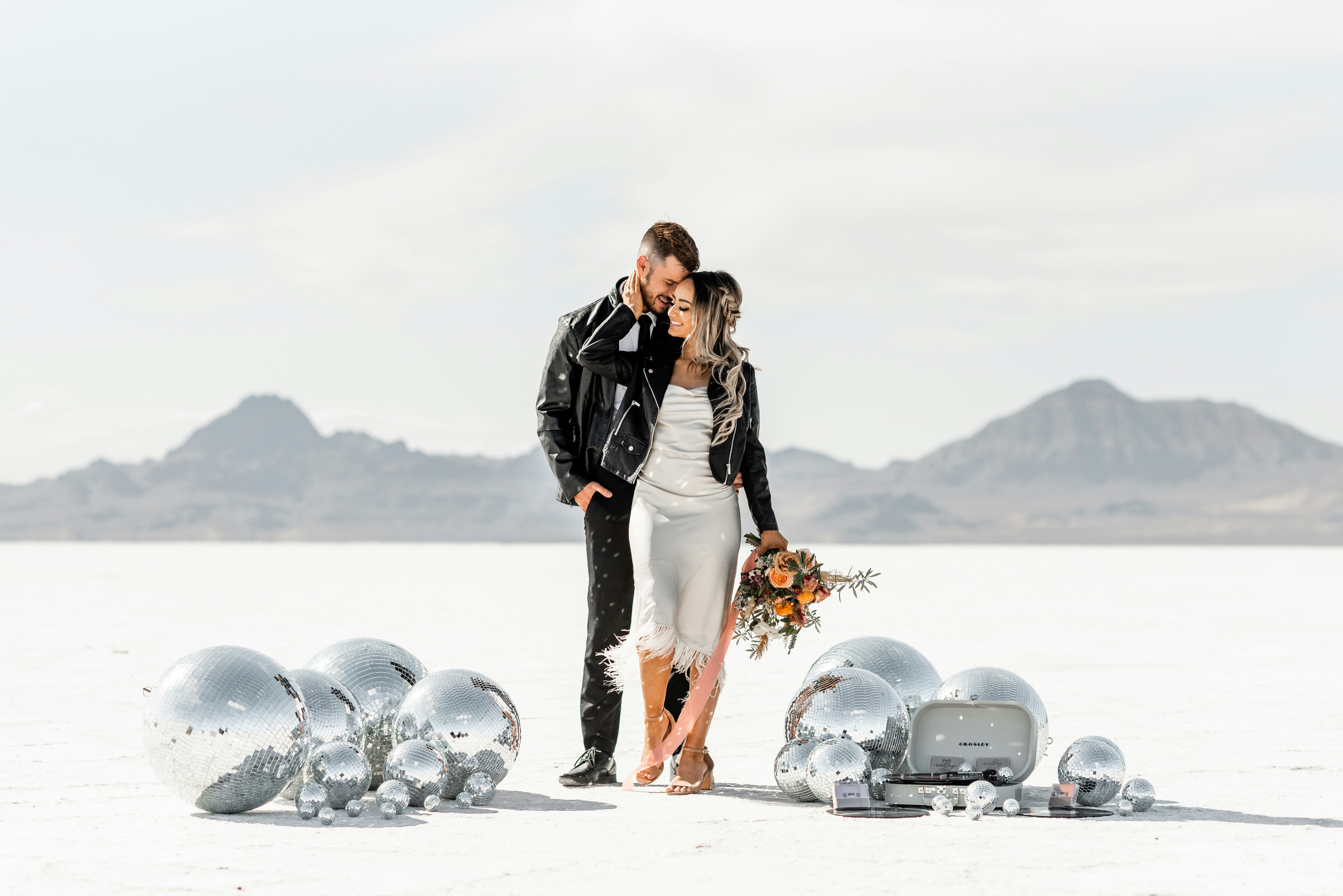 A couple stands on a salt flat surrounded by decorations
