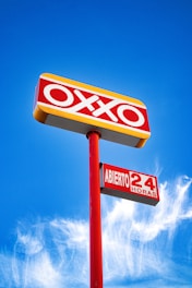 Oxxo store sign illuminated against a blue sky.