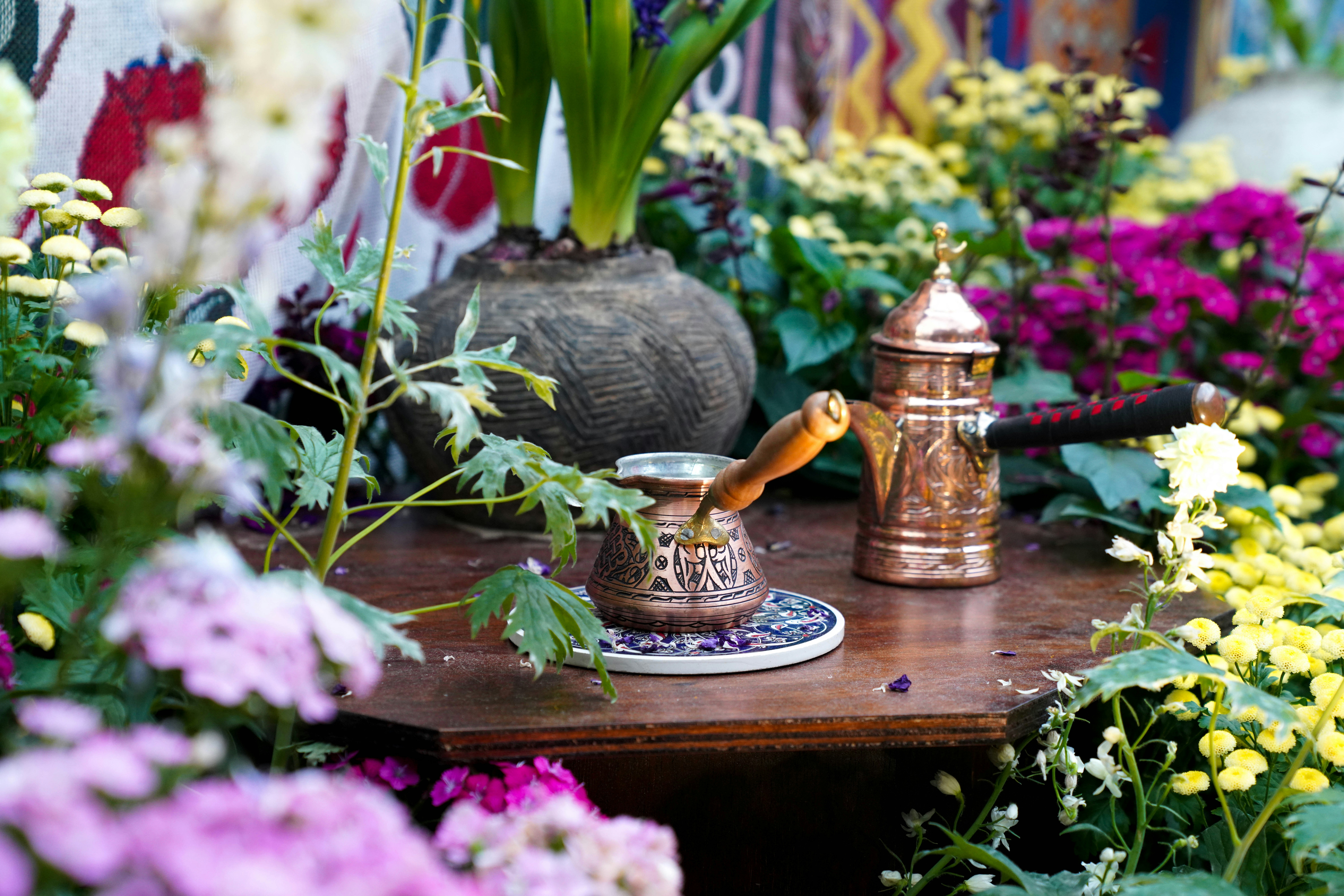 Coffee set among flowers on a wooden table.