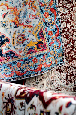 Colorful rugs are stacked for display.
