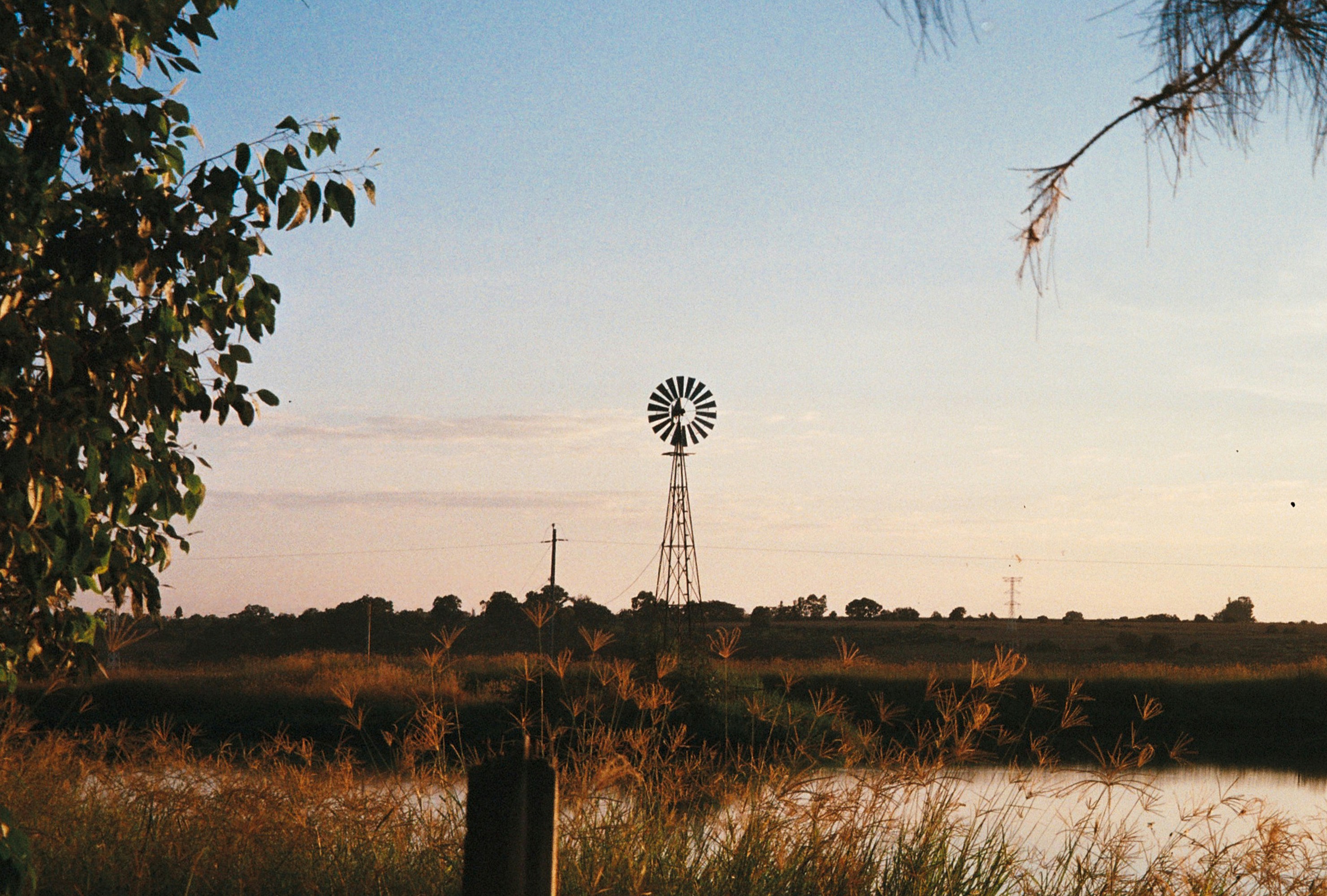 A windmill stands against a colorful sky.