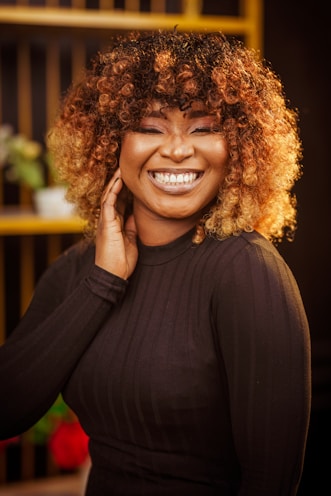 A woman smiles joyfully with beautiful curly hair.